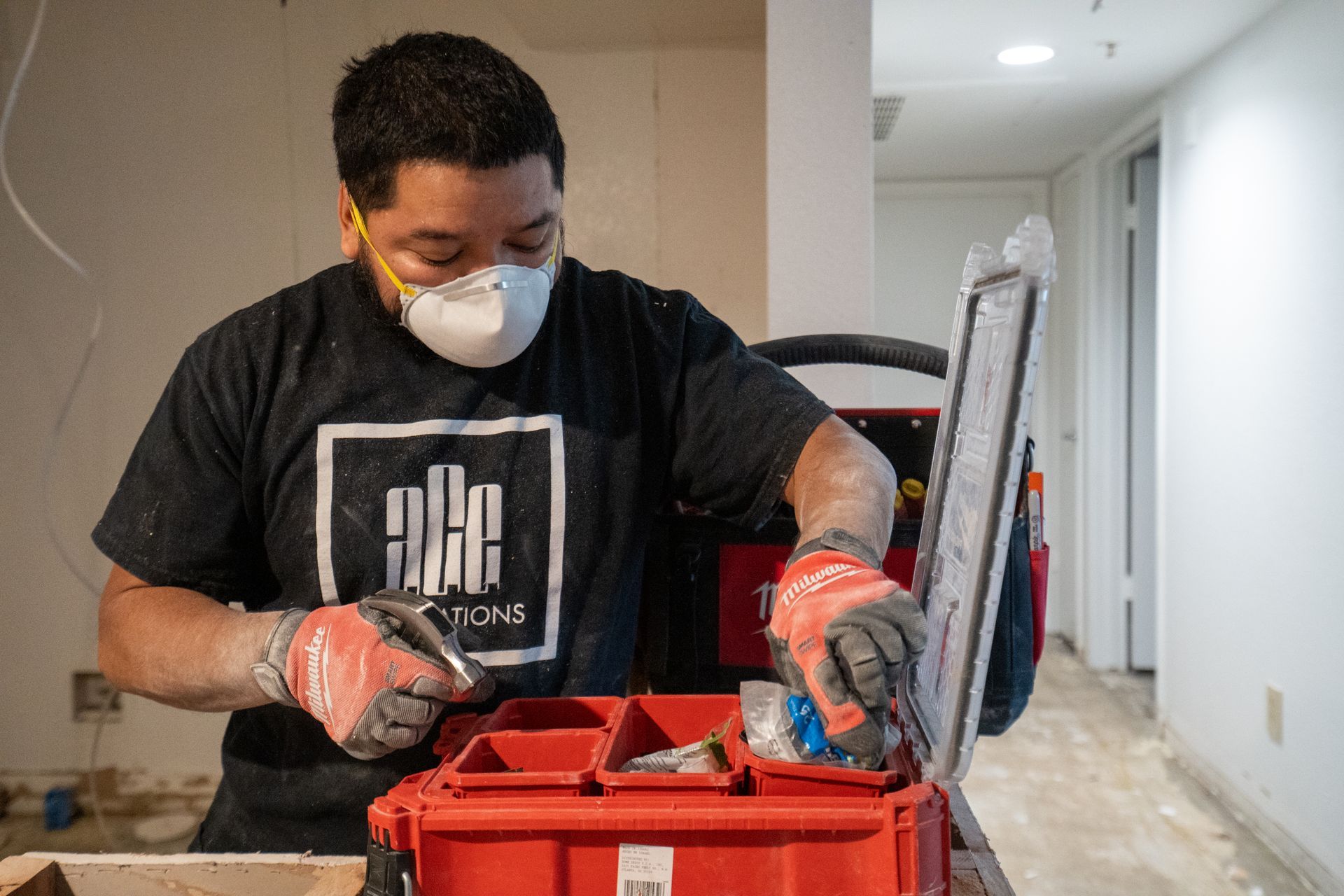 Masked worker using a red toolbox while working indoors during renovation