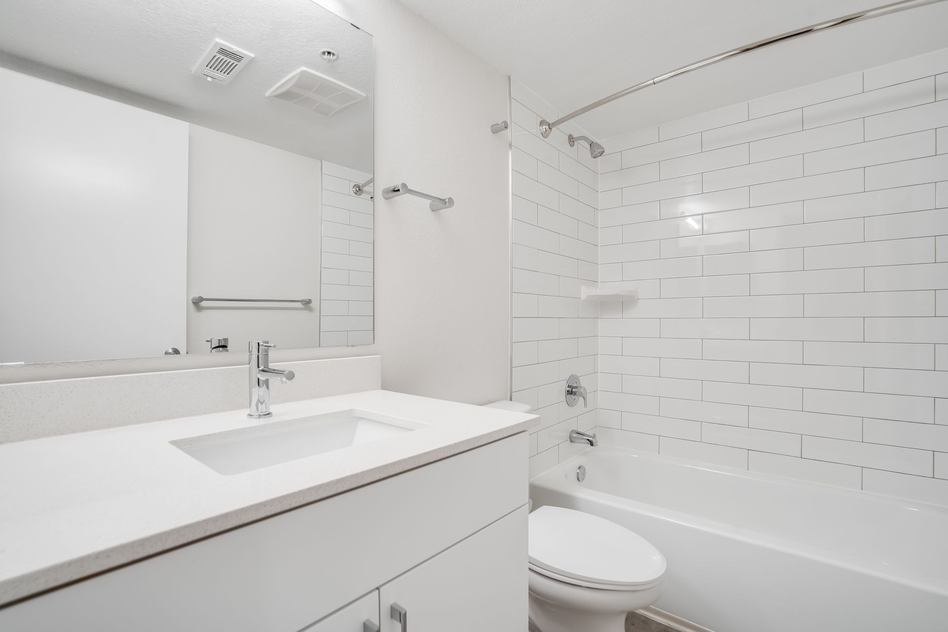 Bright white modern bathroom with vanity, mirror, sink, and tiled tub-shower surround