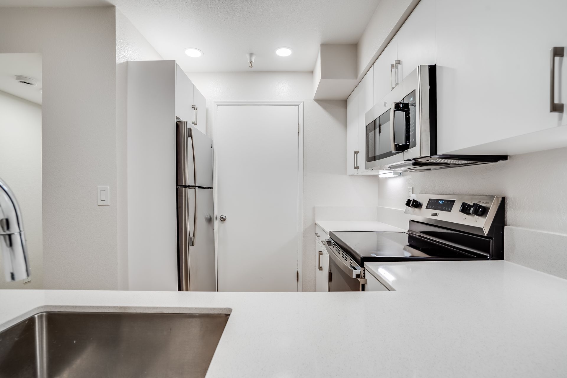 Bright modern white kitchen with stainless steel appliances and a large island countertop