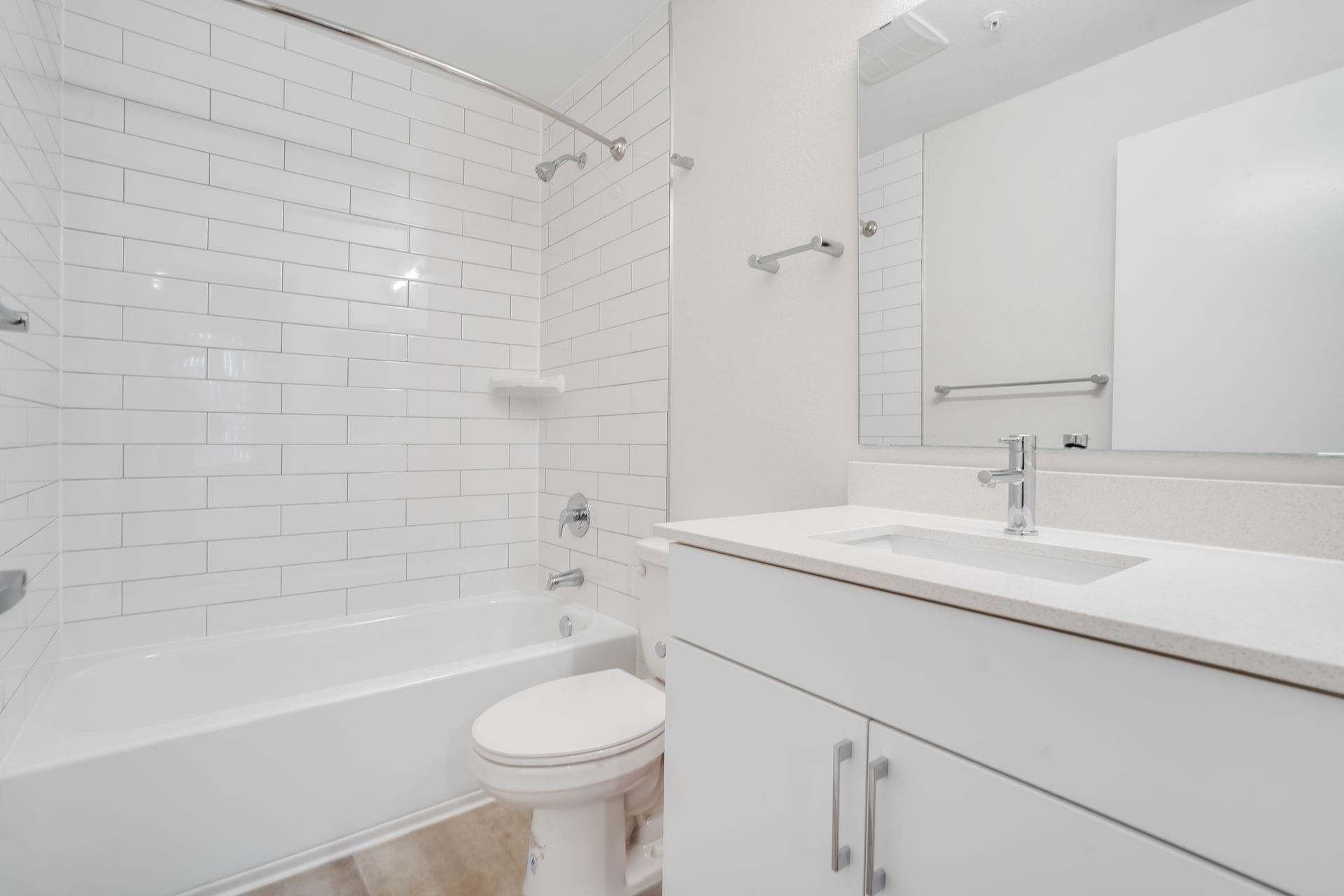 Bright white bathroom with tub, toilet, shower, and vanity sink with mirror