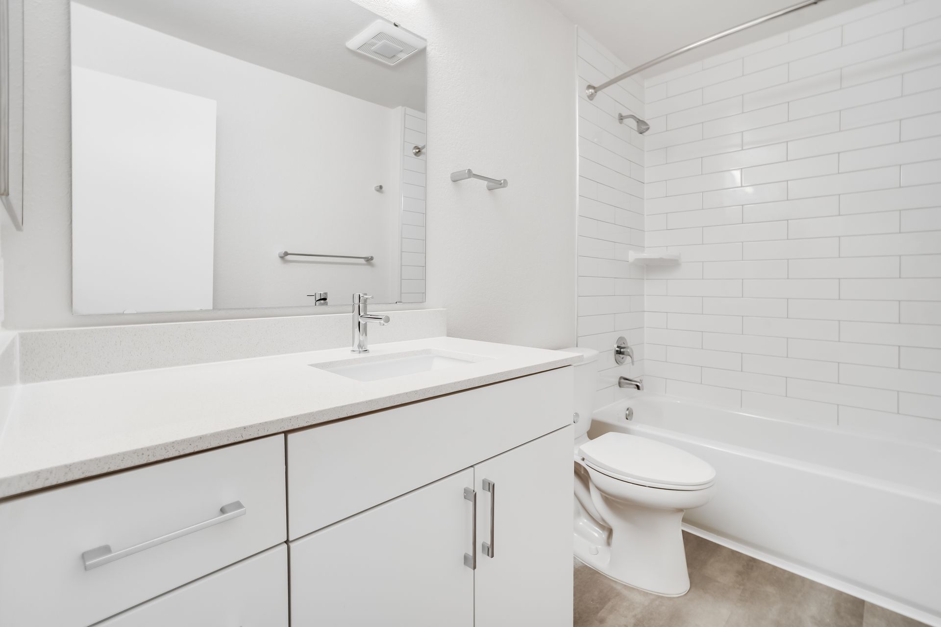 Bright white bathroom with vanity, mirror, toilet, and tiled shower stall