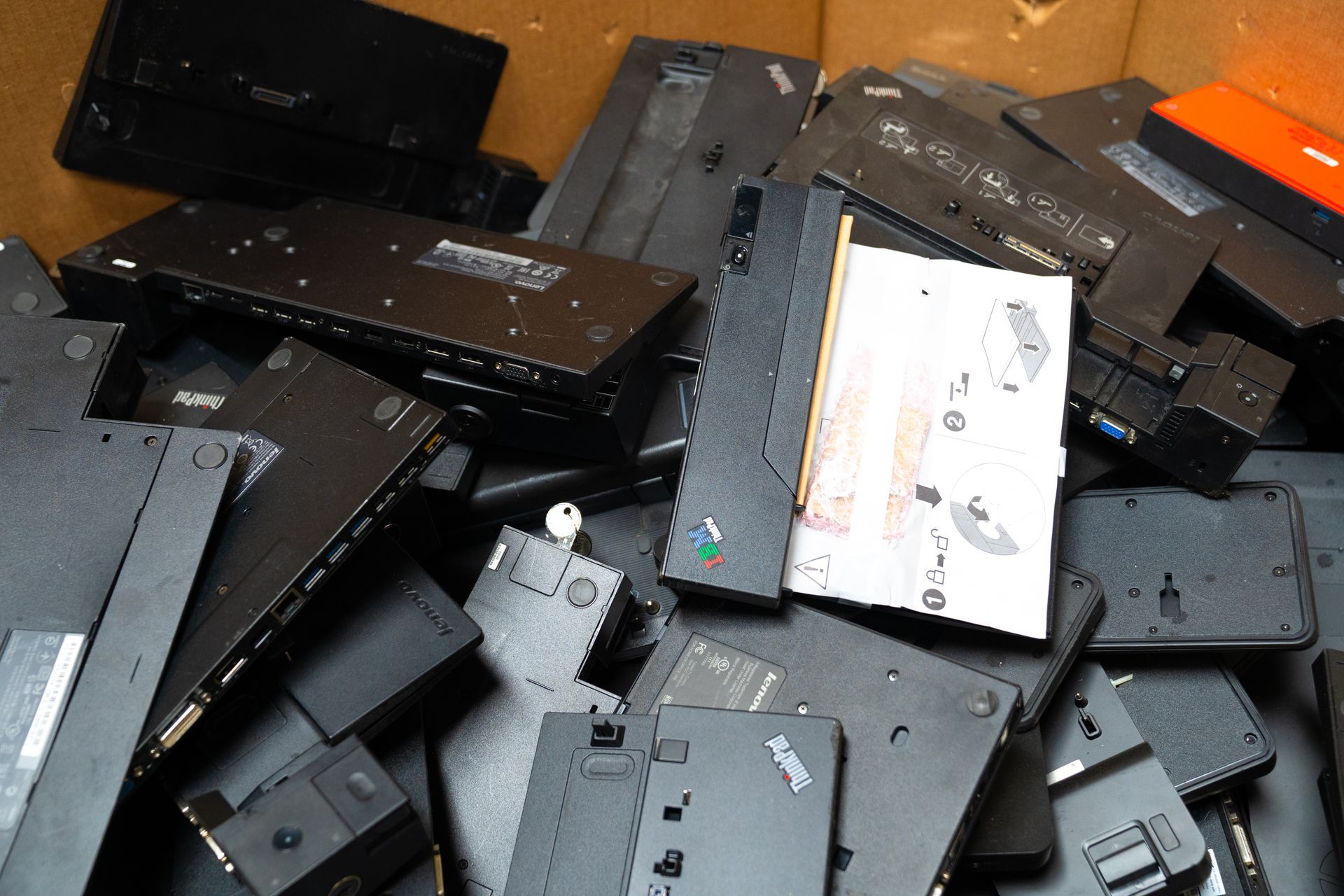 Pile of black laptop computers in a container, some with open lids.