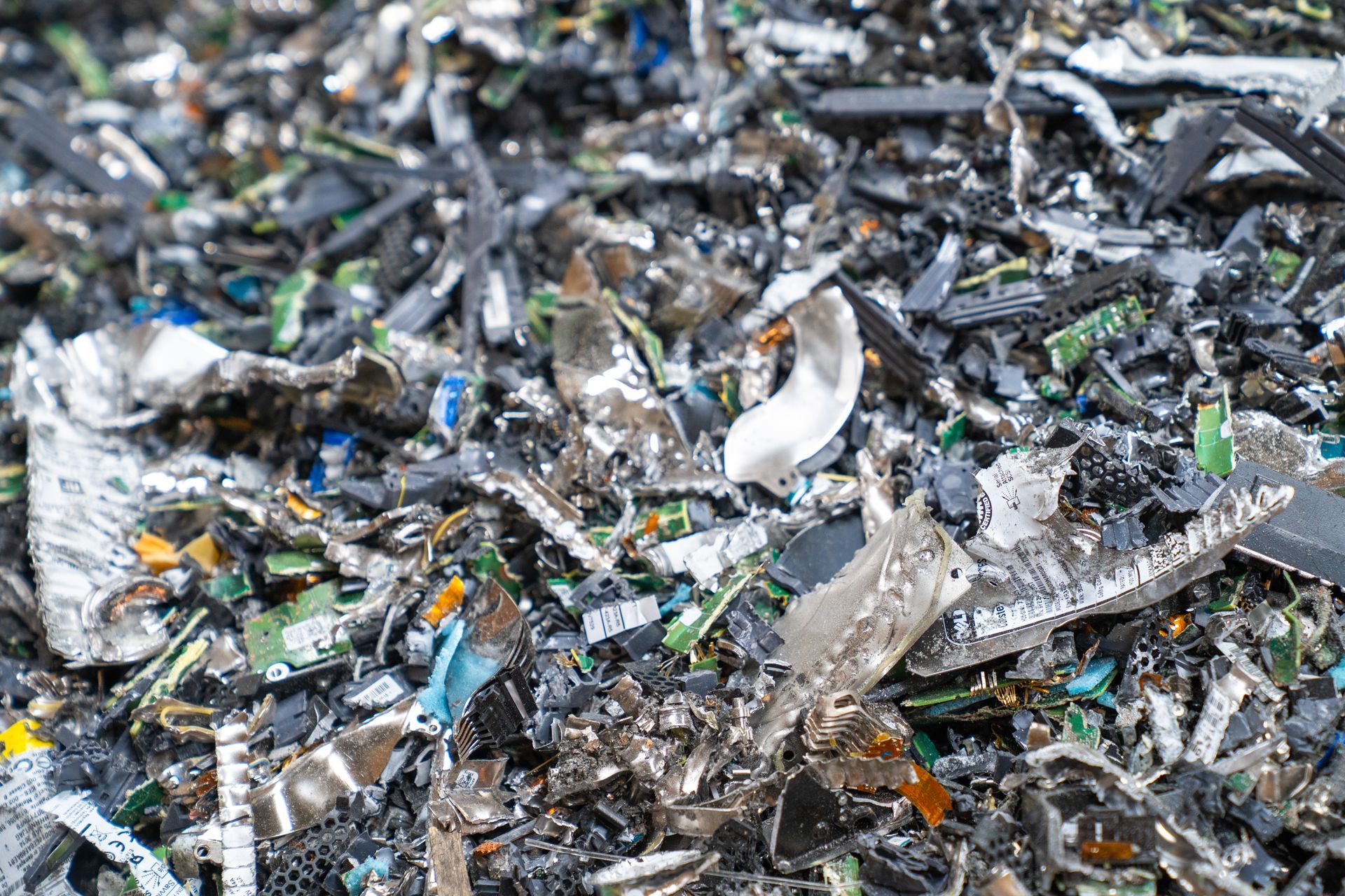 Pile of shredded electronic waste with circuit boards and plastic components.