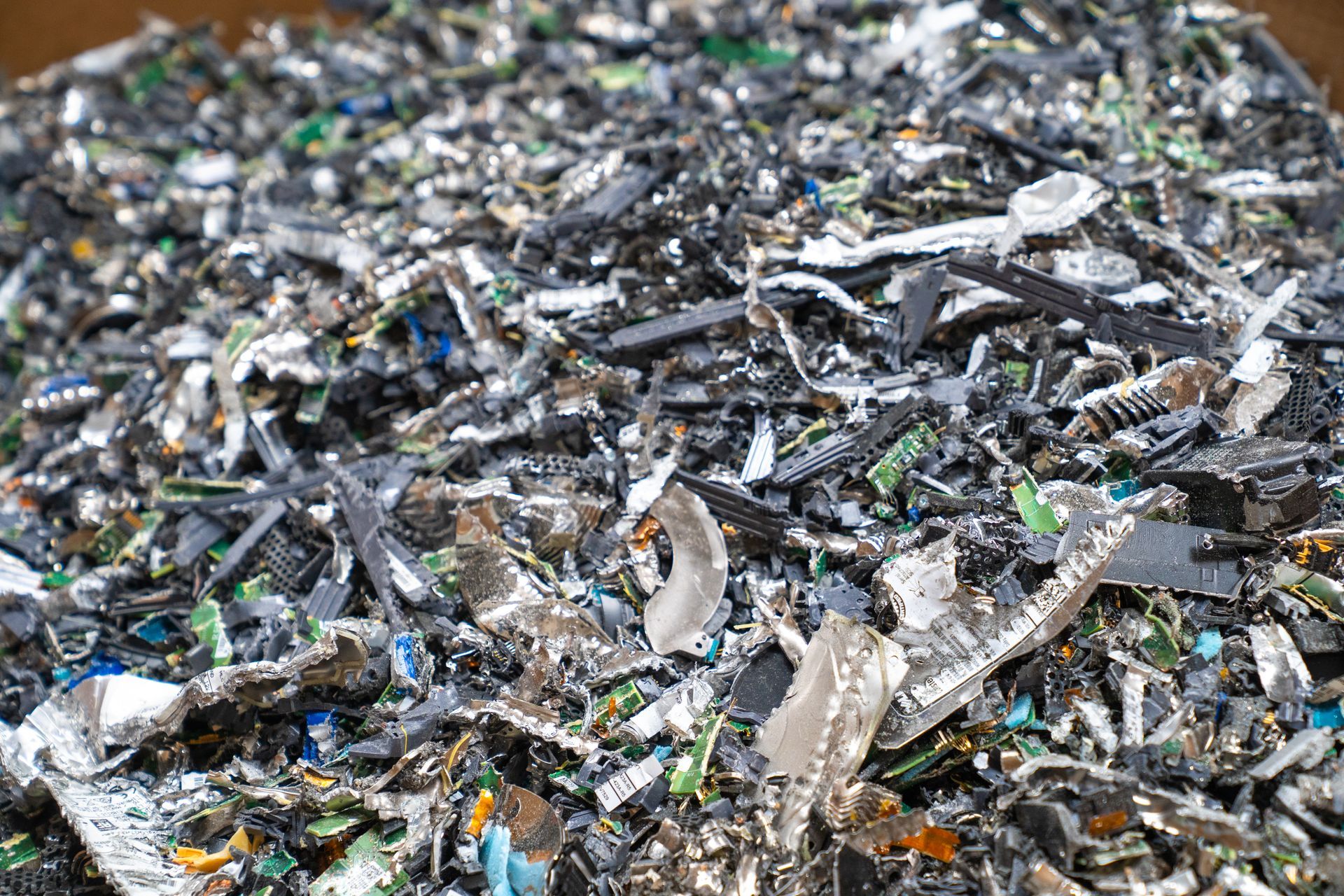 Heap of electronic circuit board scraps, green, black, and silver.