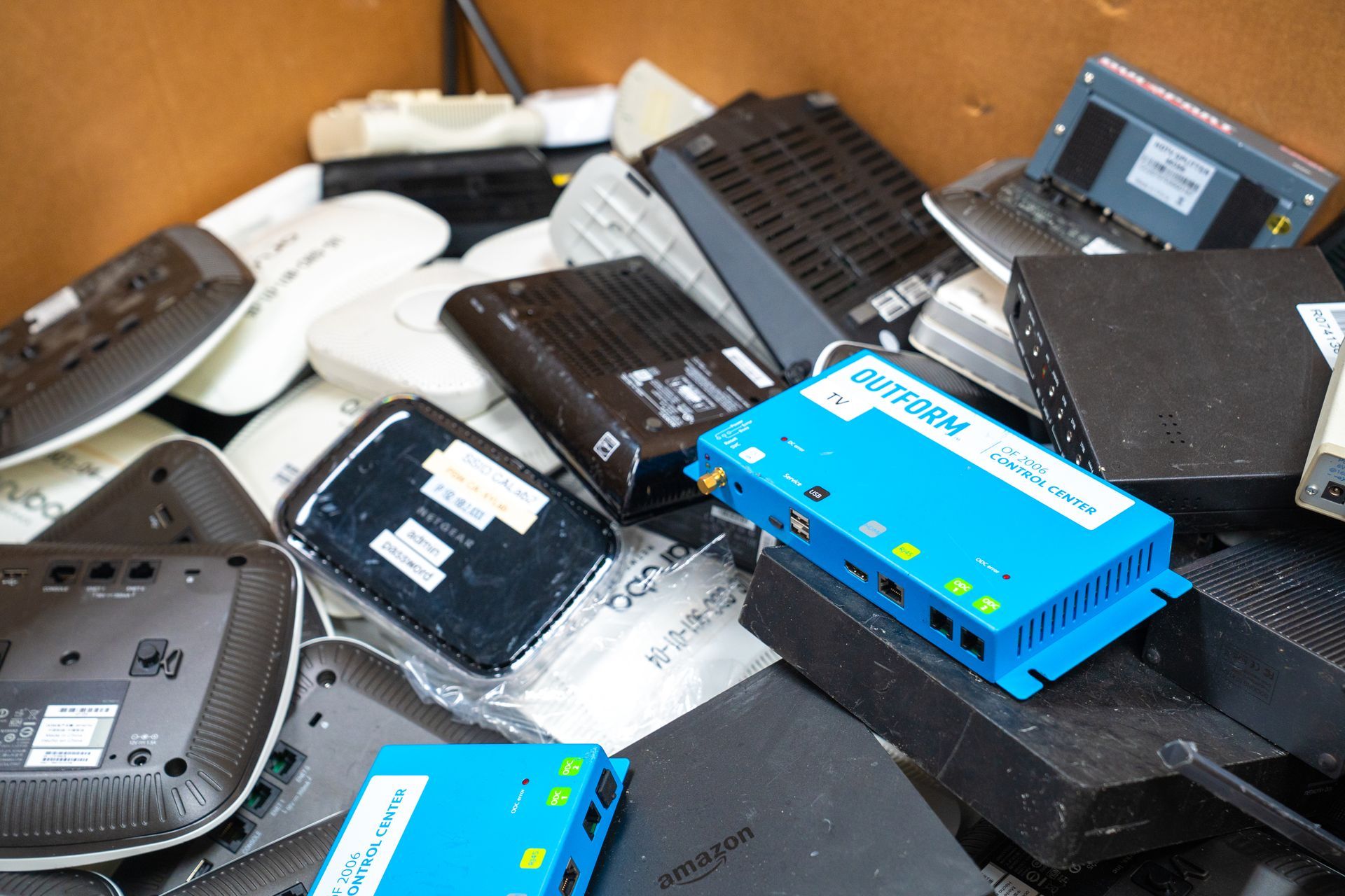 Box filled with various discarded electronics, including routers and modems.