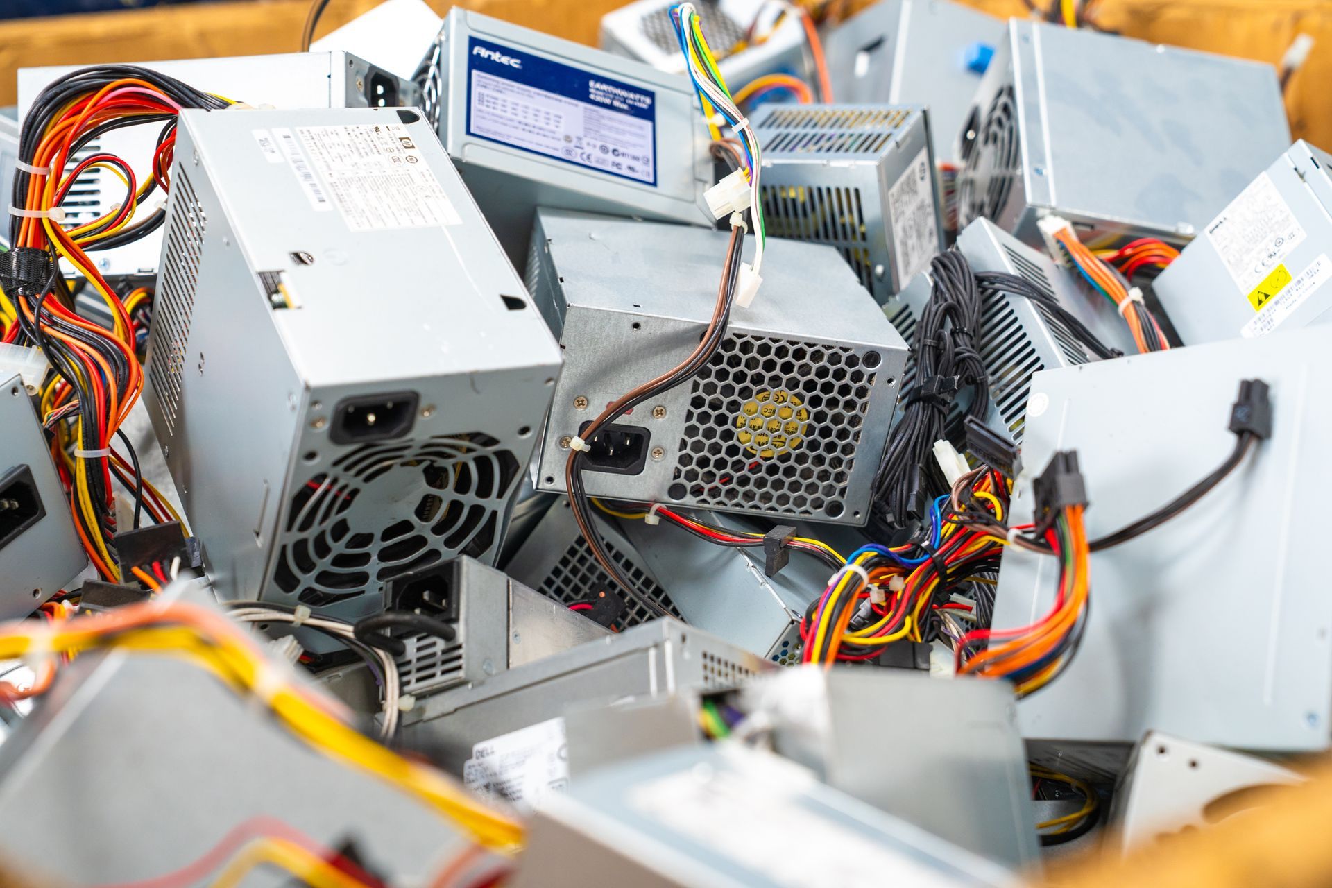 Pile of old computer power supply units with wires, ready for recycling.