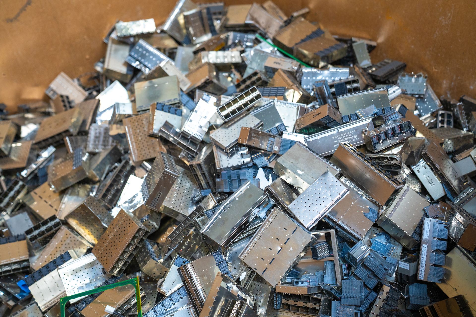 Pile of assorted metal computer components in a container, possibly for recycling.
