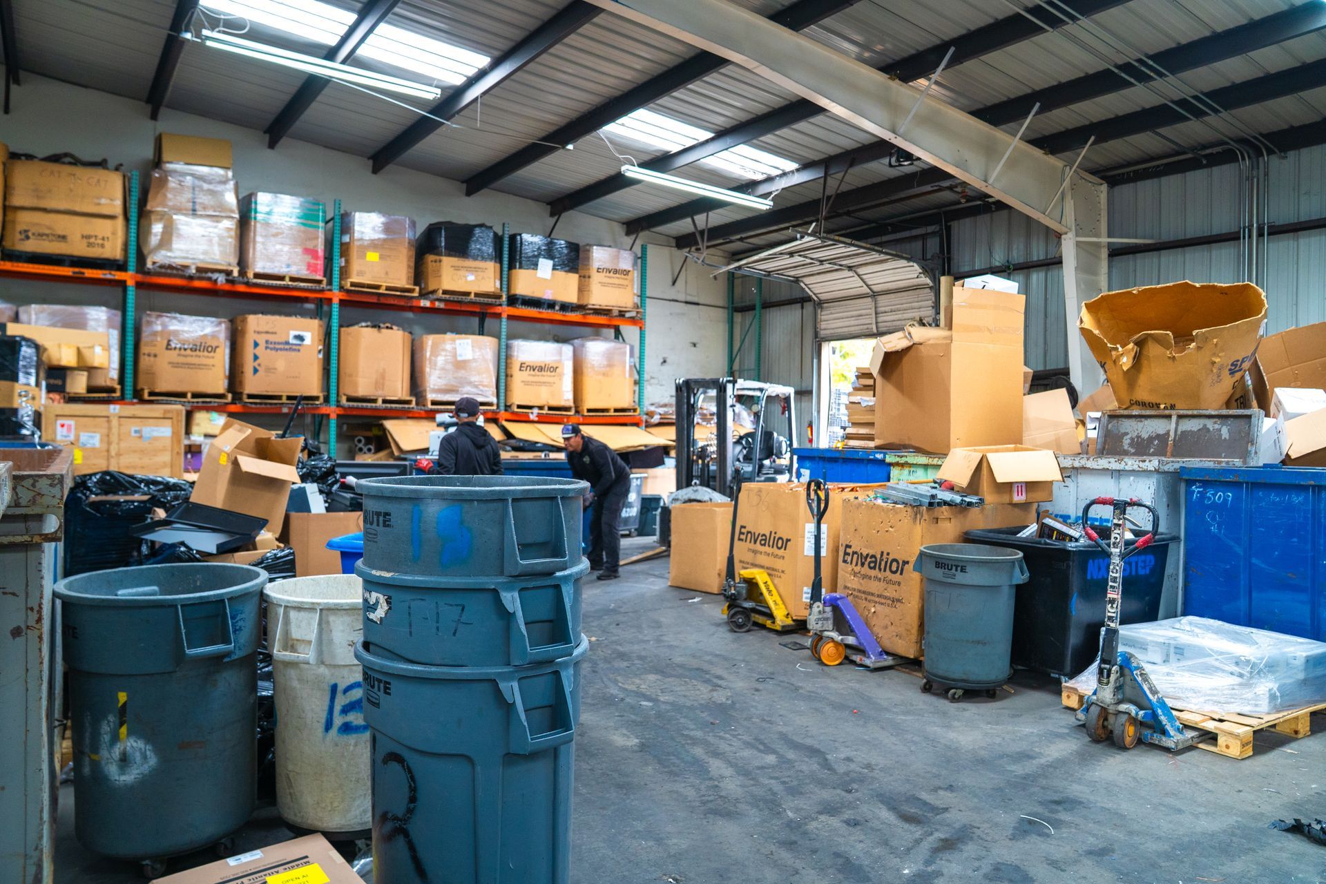 Warehouse with cardboard boxes and bins stacked, with a person sorting items.