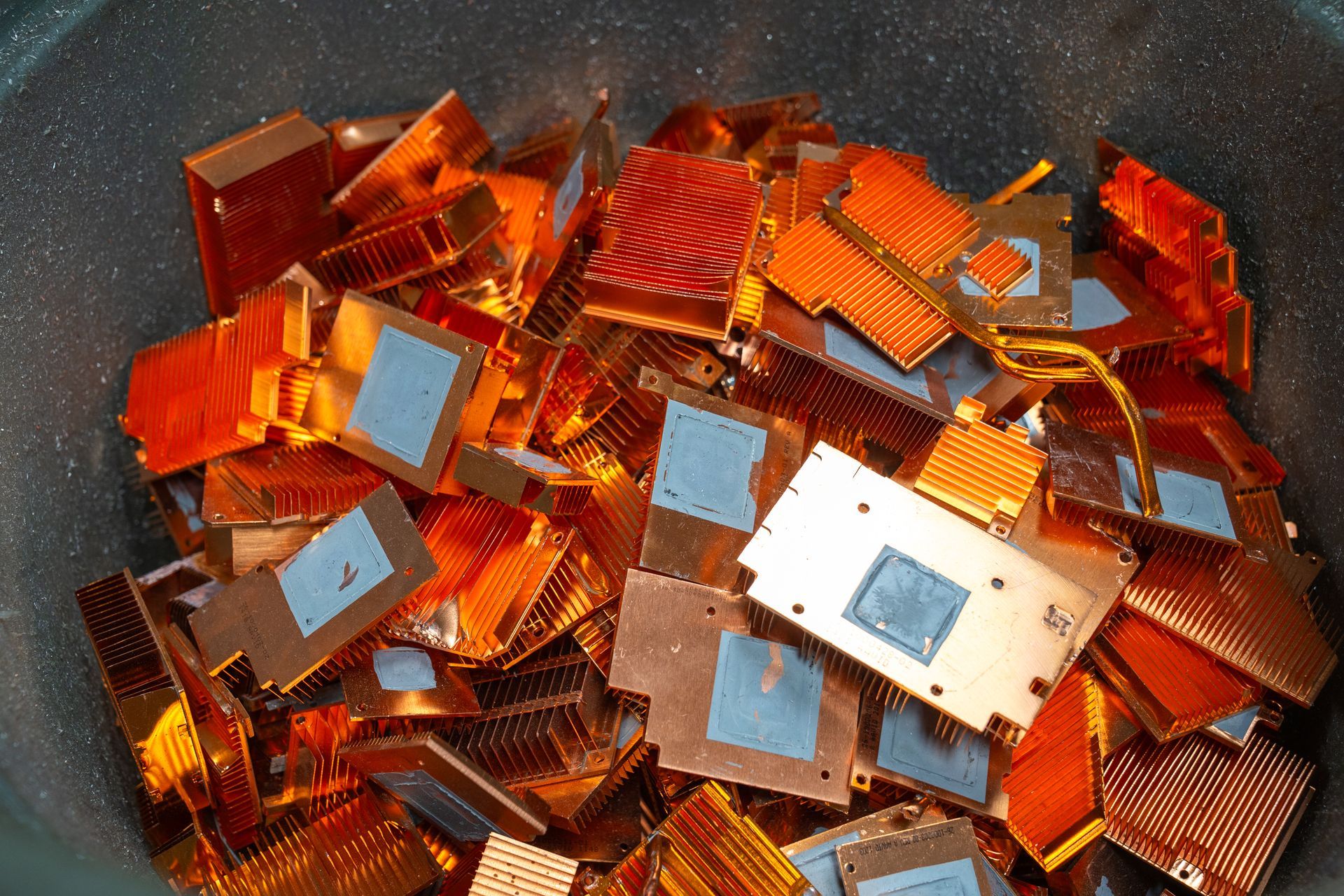 Pile of copper CPU heat sinks in a metal container.