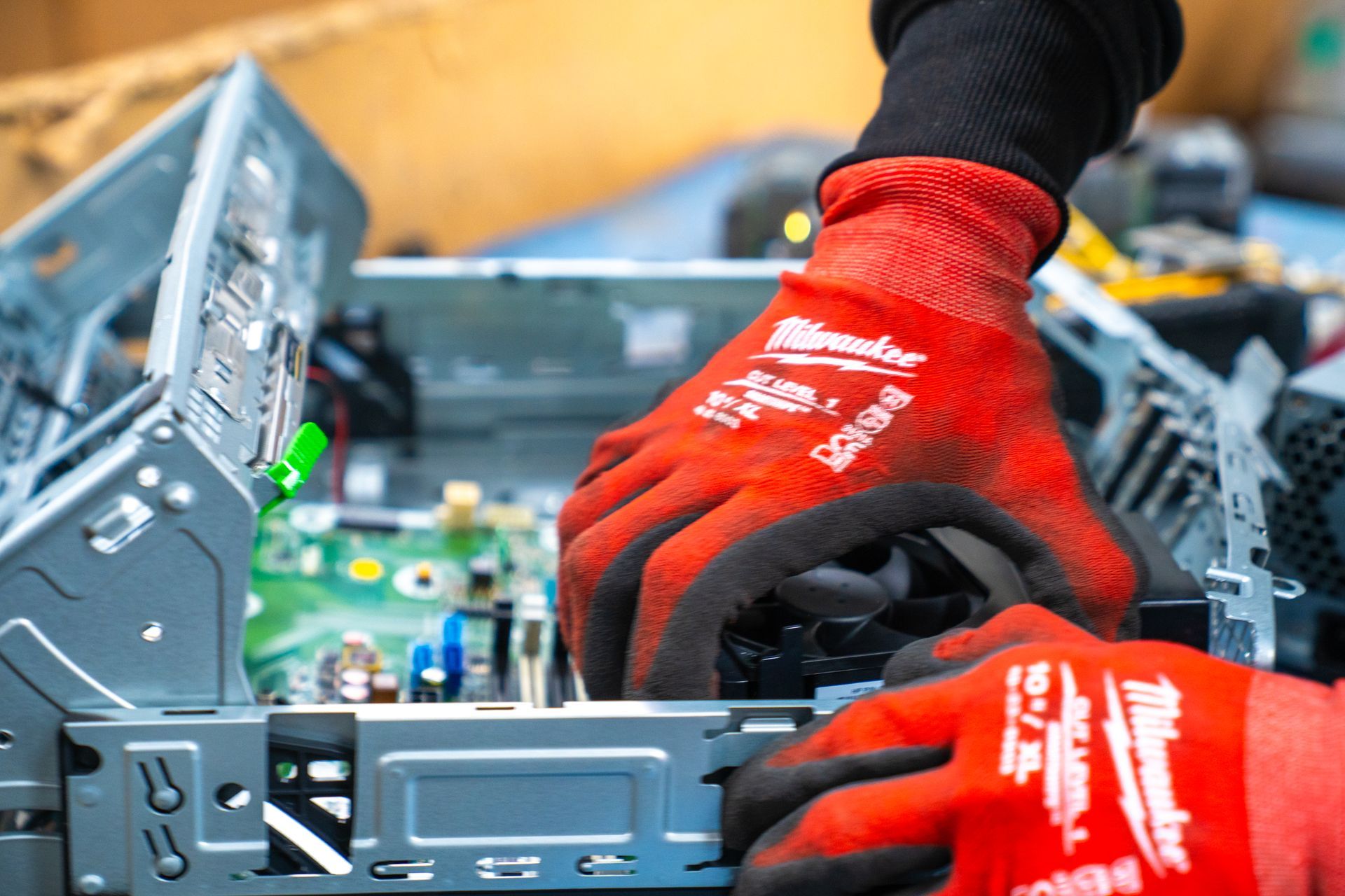 Hands in red gloves working inside a computer, likely repairing or assembling components.