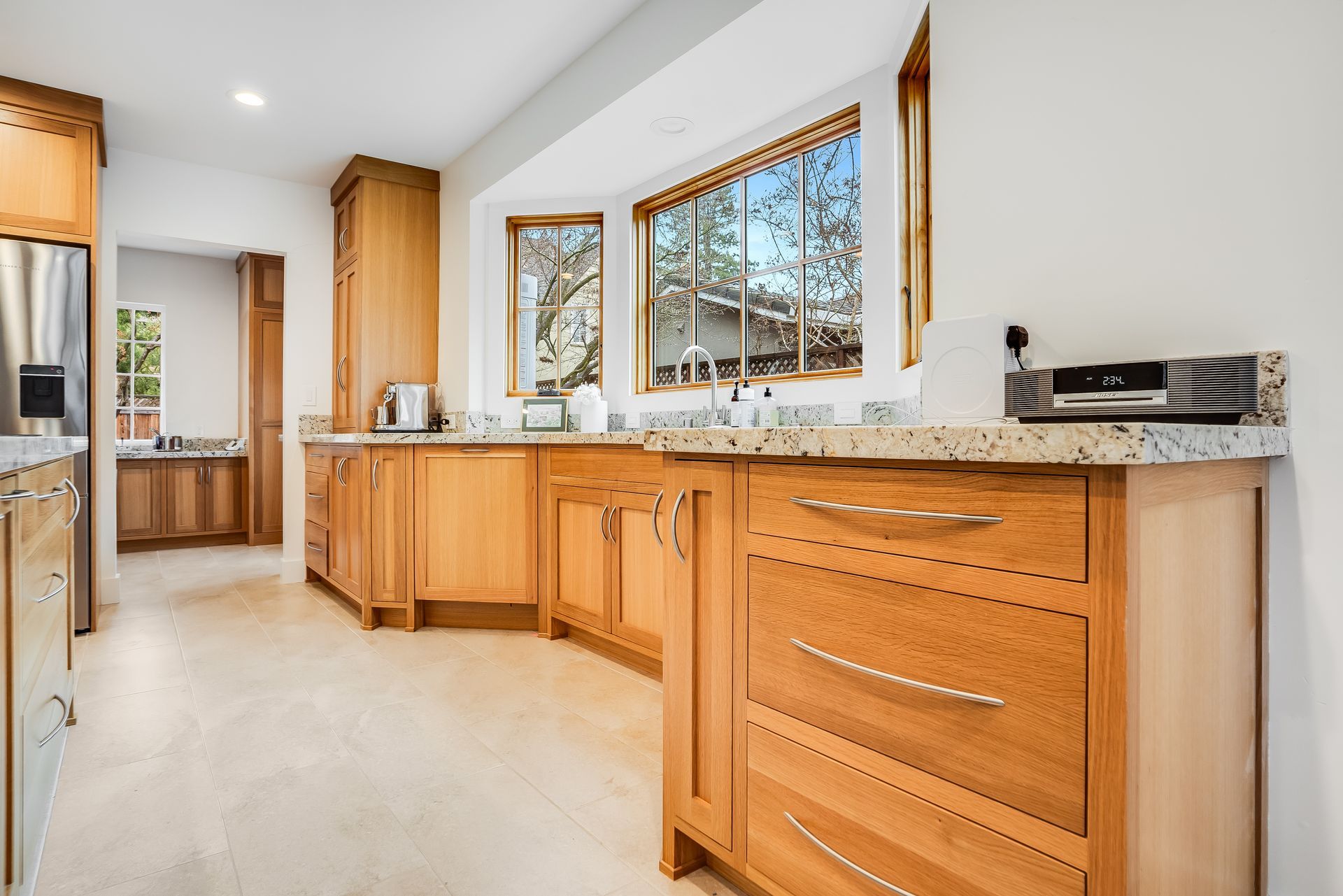 Bright kitchen with wooden cabinets, granite countertops, and a large window over the sink