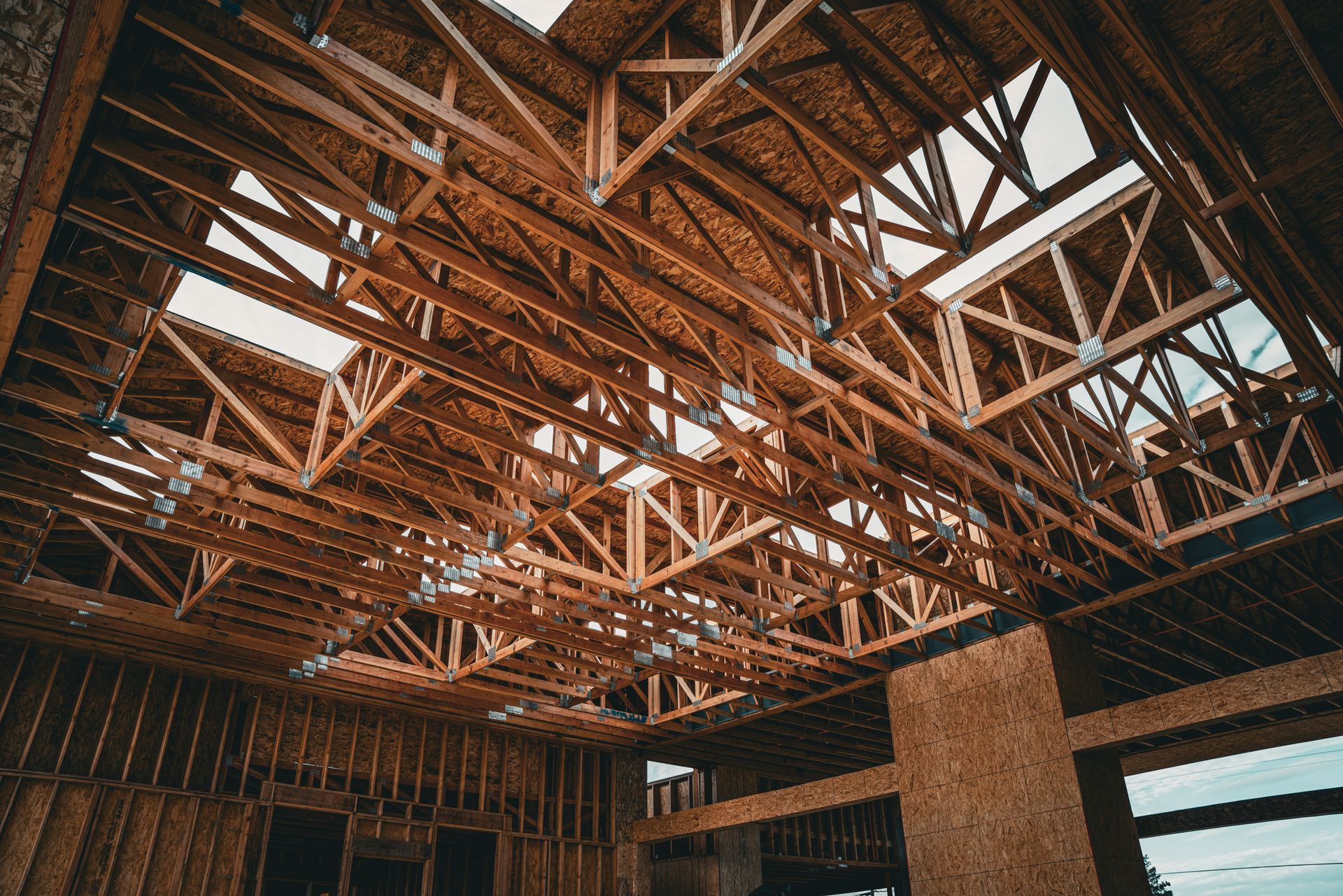 Exposed wooden trusses and skylights inside a partially built structure under construction