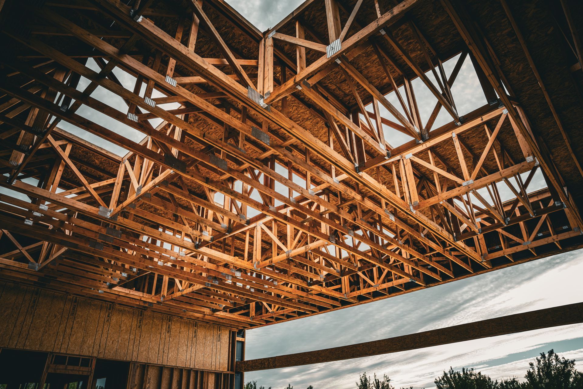 Wooden roof trusses inside an unfinished building, seen from below