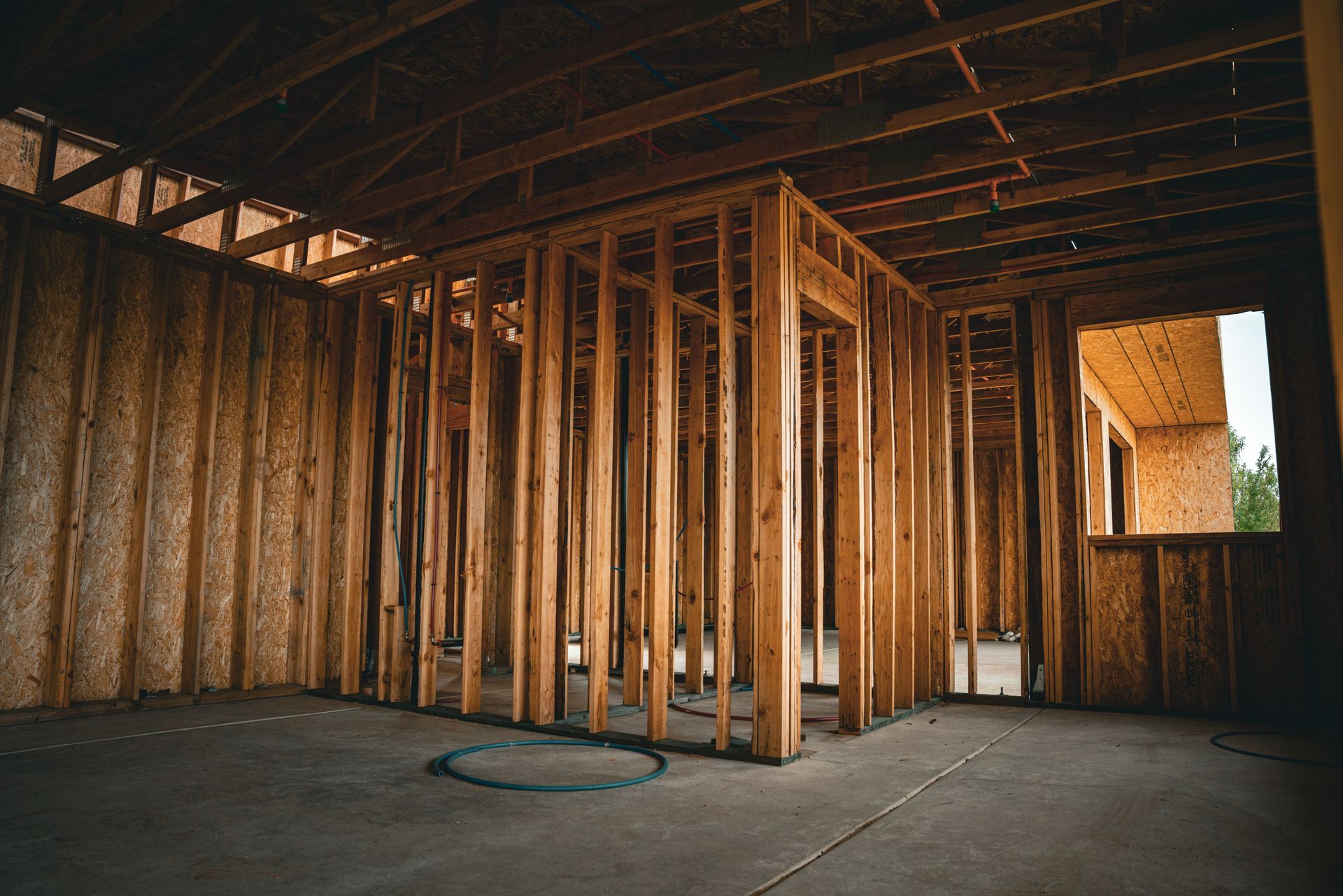 Framed interior of a building under construction with exposed wooden studs and a concrete floor.