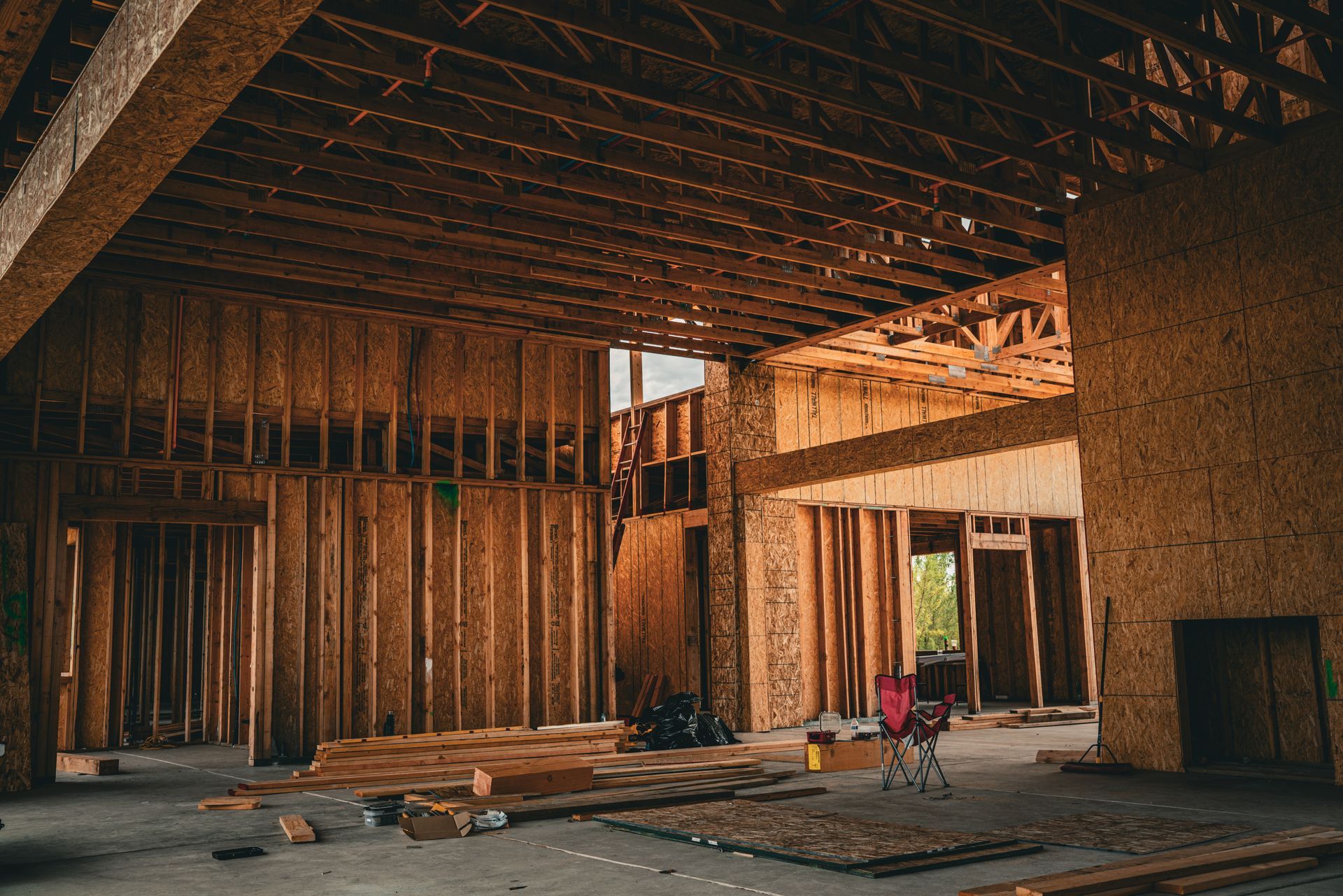 Abandoned unfinished building interior with exposed wood framing, concrete floor, and debris scattered around.
