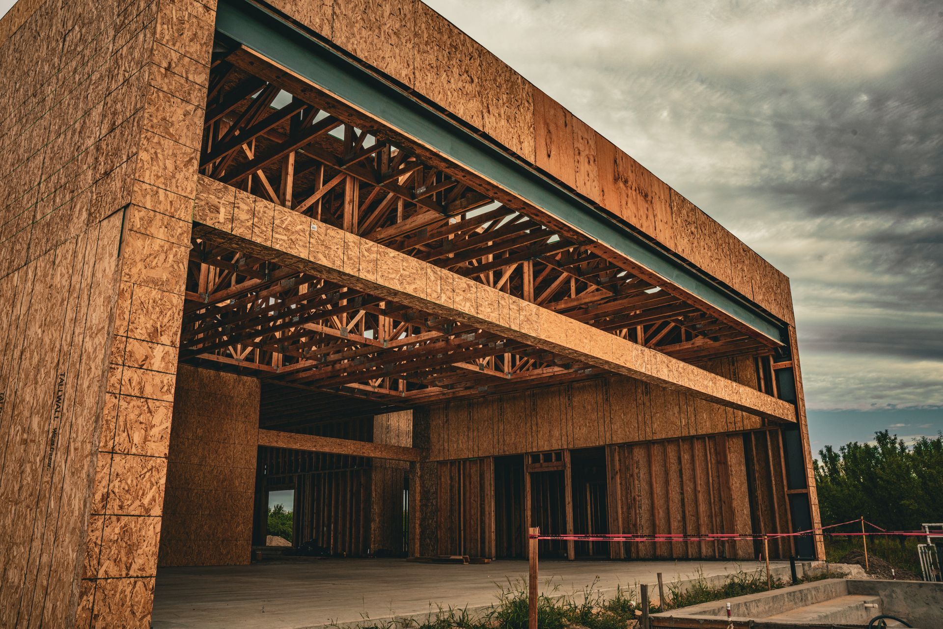 Partially built brick building with exposed wooden framing under a cloudy sky
