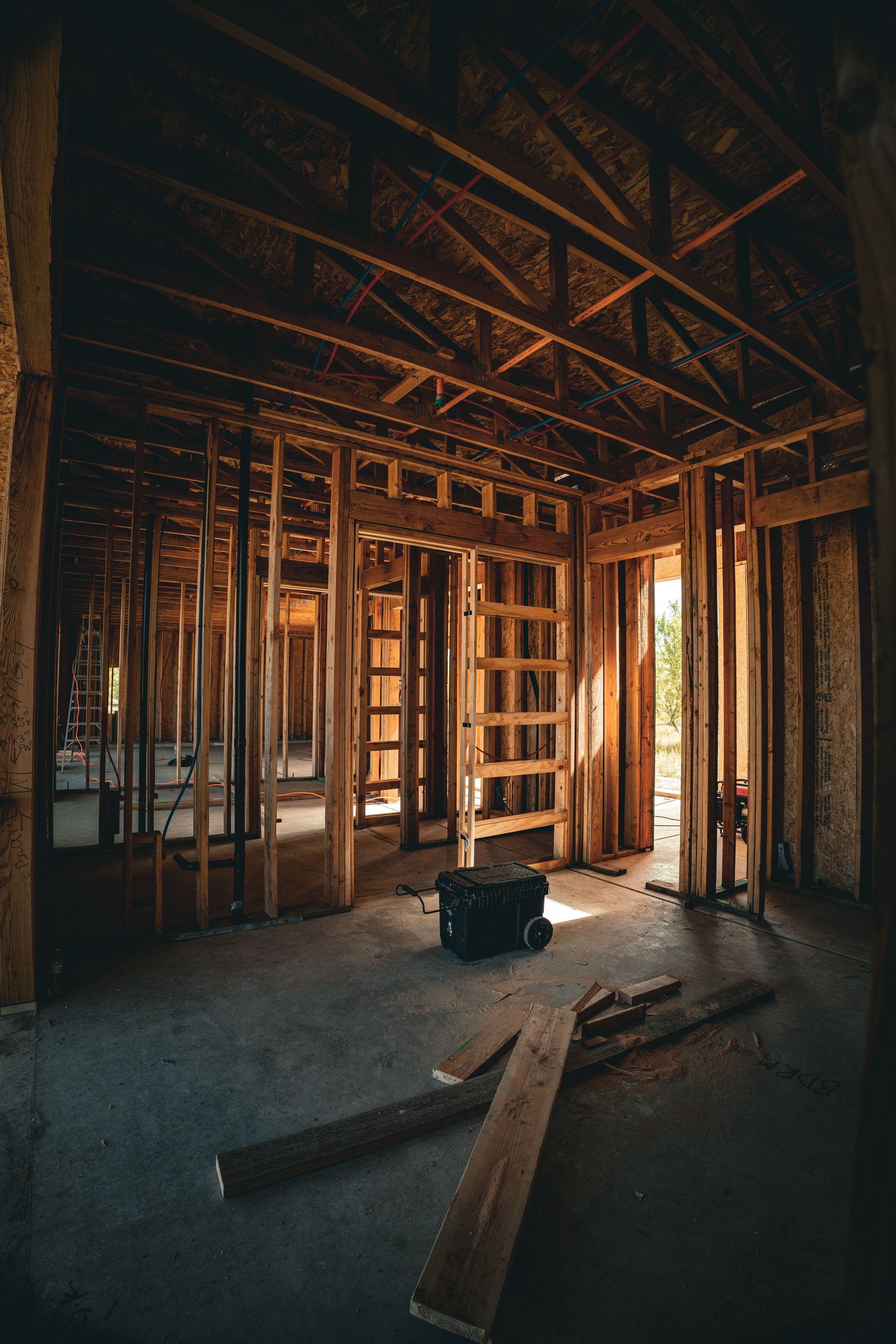 Partially framed room under construction with exposed beams, wood studs, and sunlight through window openings