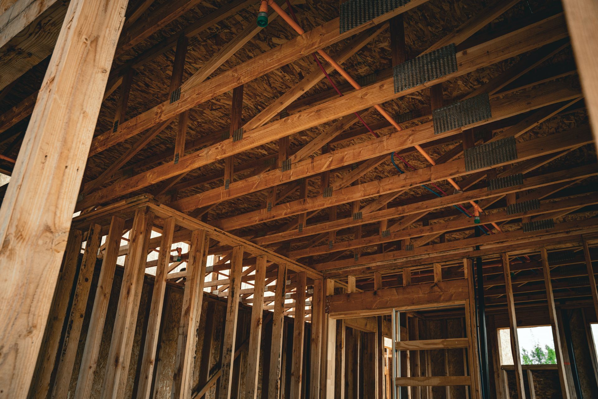 Wooden house framing with exposed rafters and studs inside an unfinished interior