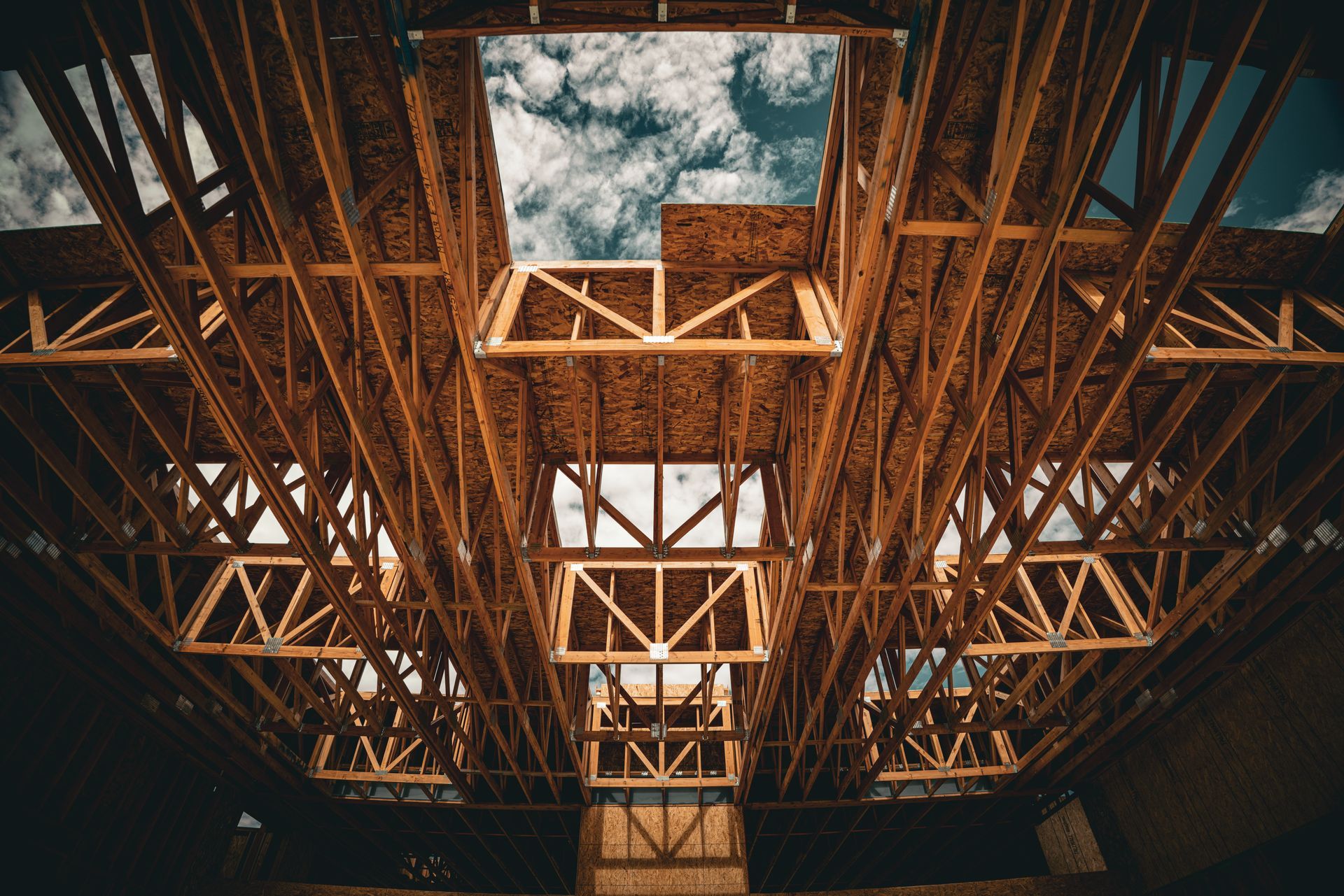 Wooden ceiling beams framing sky through skylights in an industrial interior