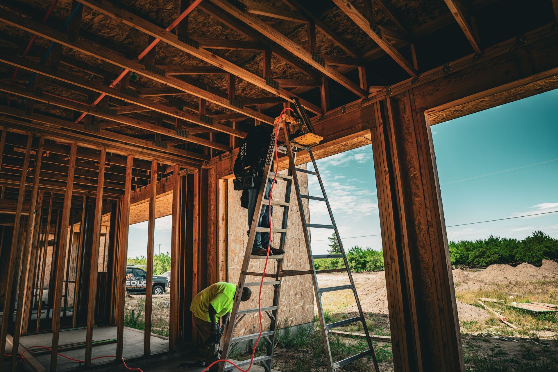 Construction workers framing a wooden house interior with a ladder and exposed beams