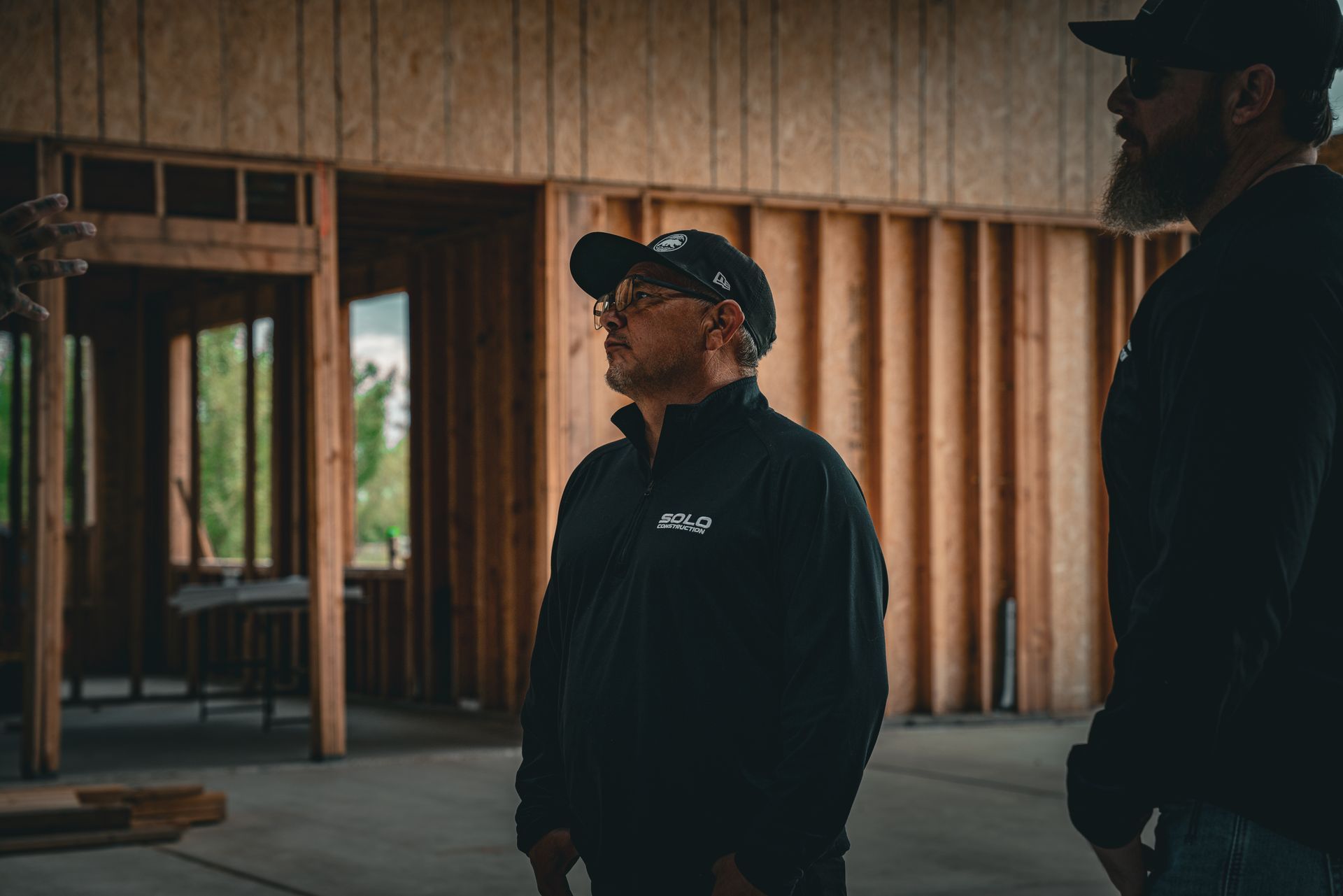 Two men in dark clothing standing inside a partially built wooden structure.
