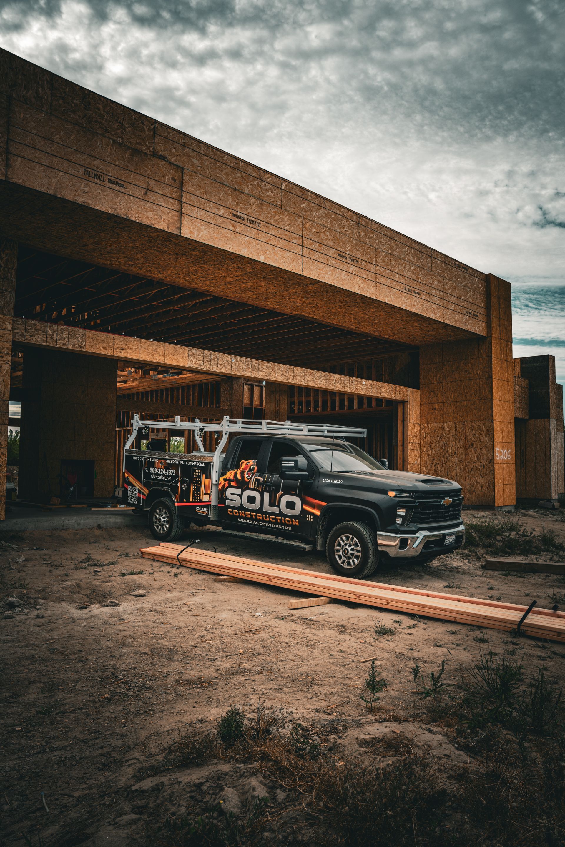 Black off-road truck parked outside a modern brick building under a cloudy sky
