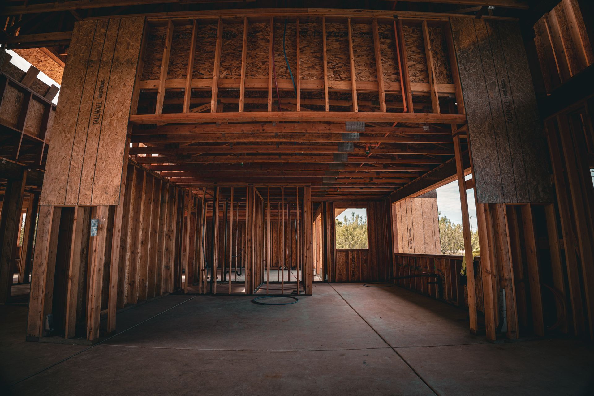 Interior of a house under construction, with exposed wooden framing and daylight through windows.