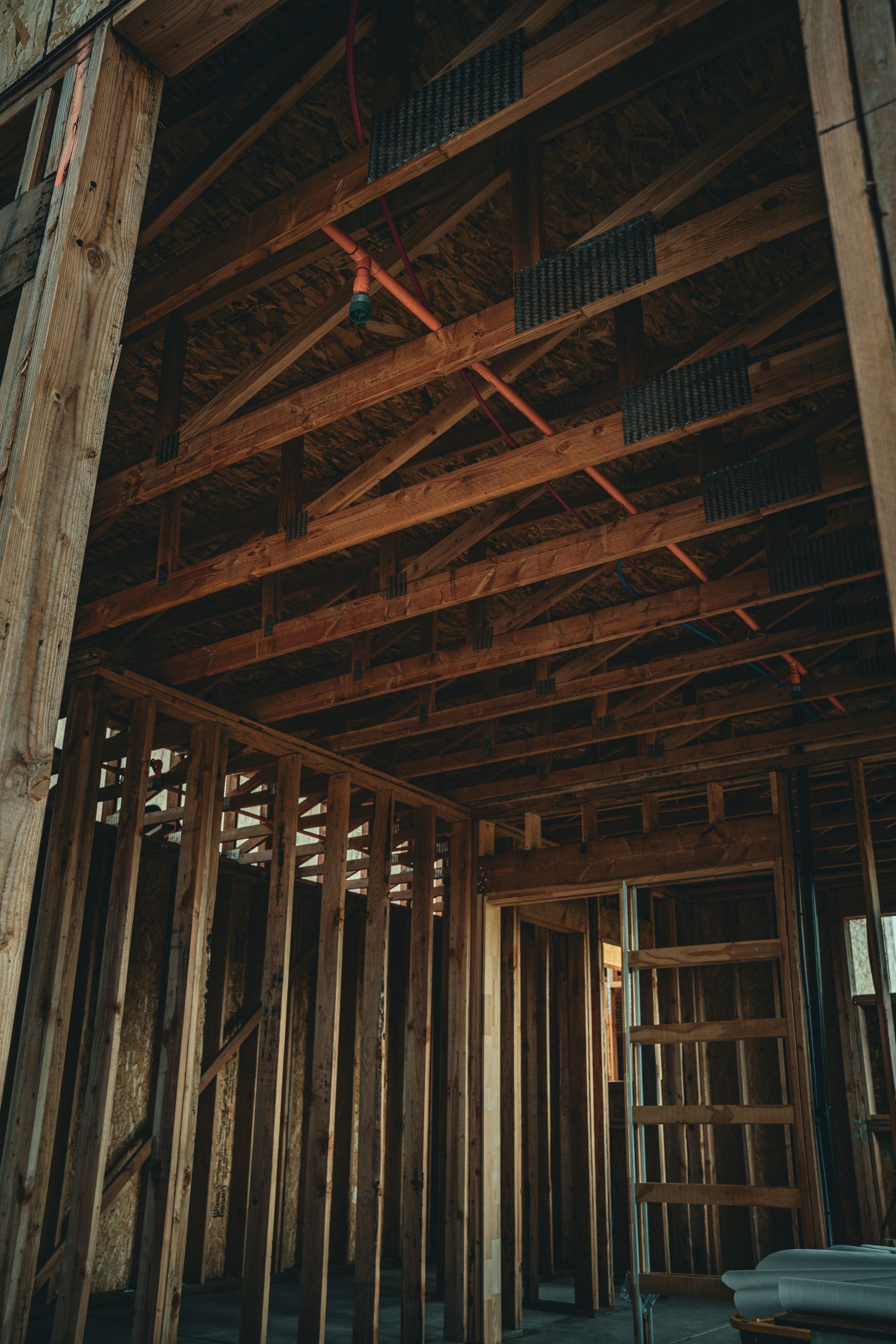 Unfinished wooden room with exposed studs, ceiling beams, and a doorway under construction