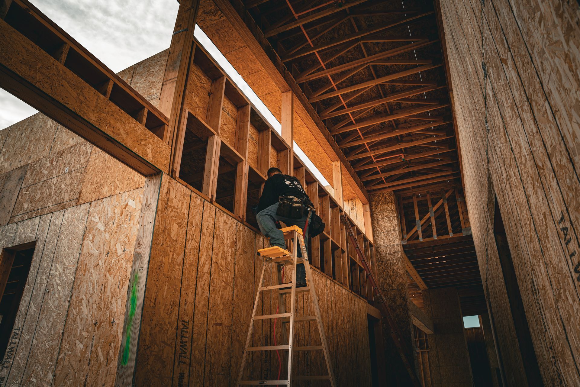Worker climbing a ladder inside a wooden building under construction