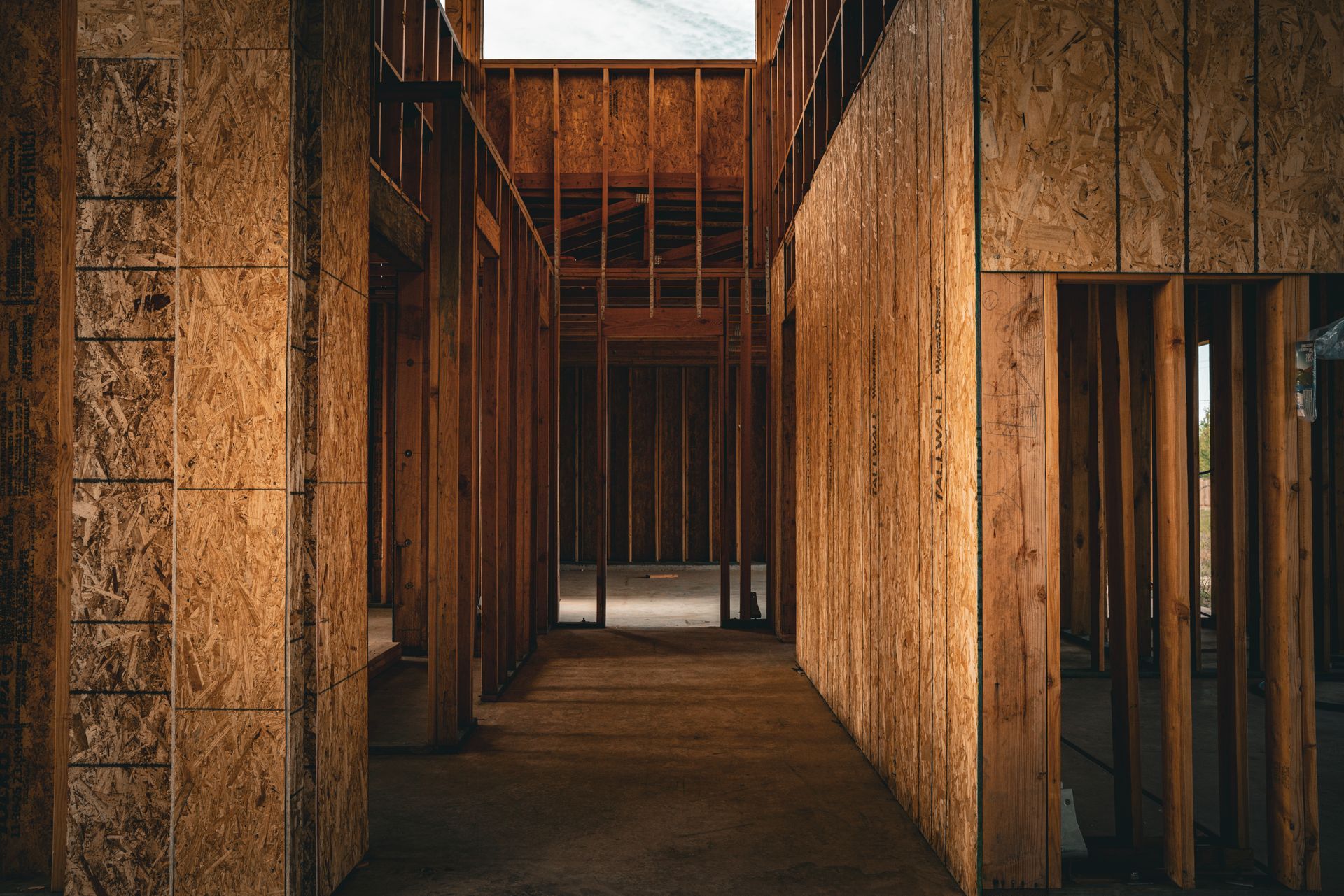 Unfinished wooden hallway with exposed studs and narrow door openings in a construction site