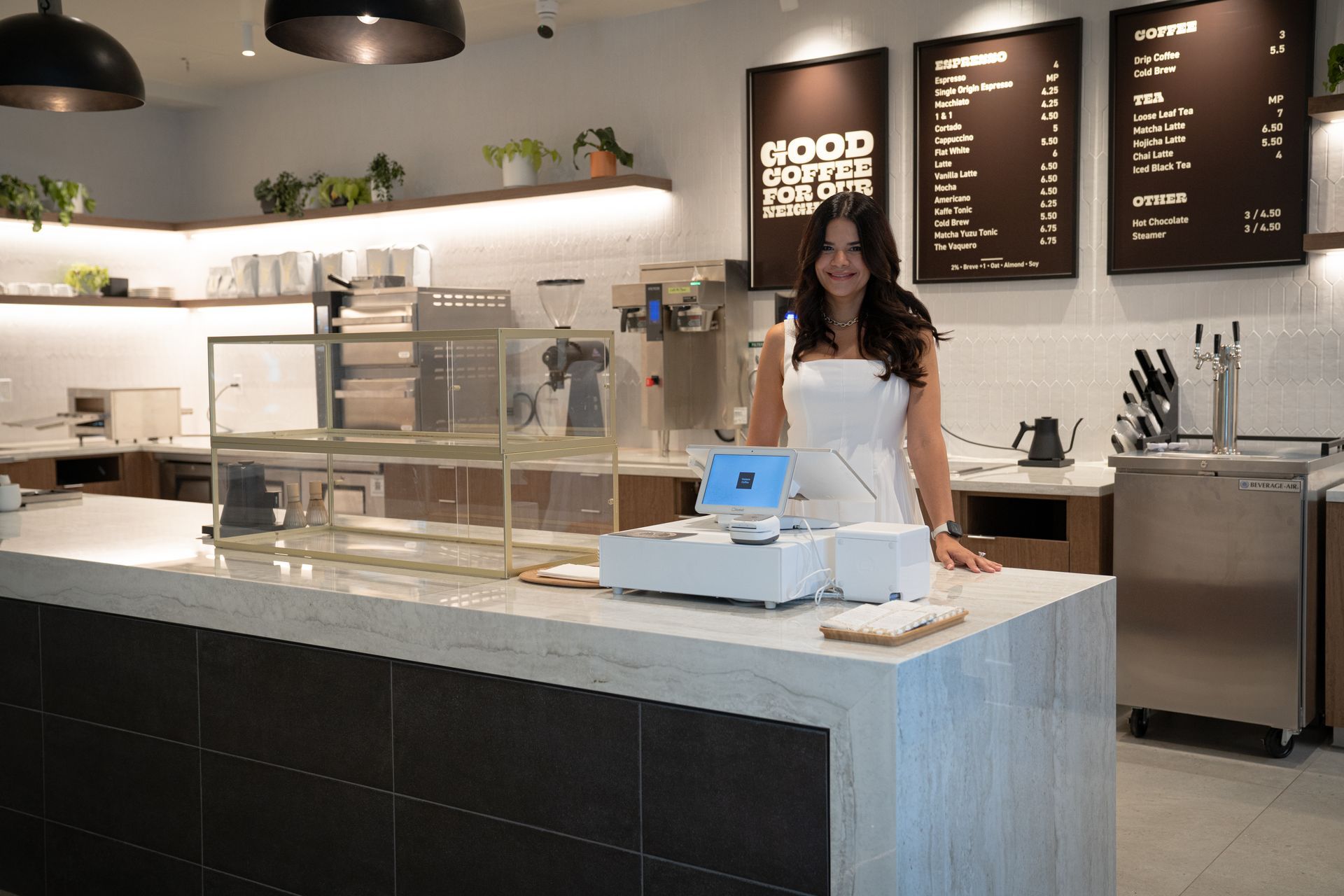 Bakery counter with display cases, menu boards, and a staff member standing behind the register