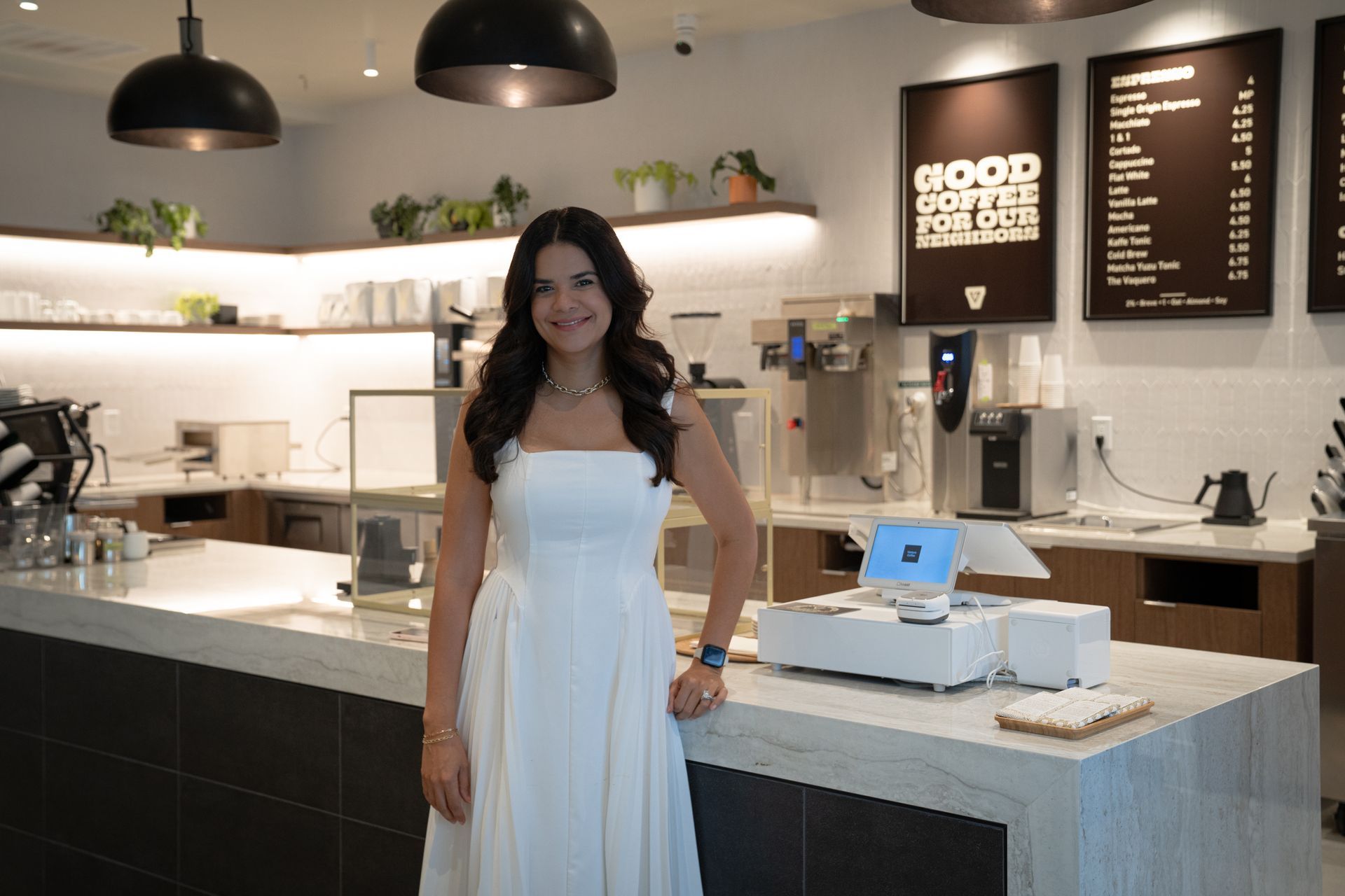 Woman standing in a modern café with hanging lights and a counter display
