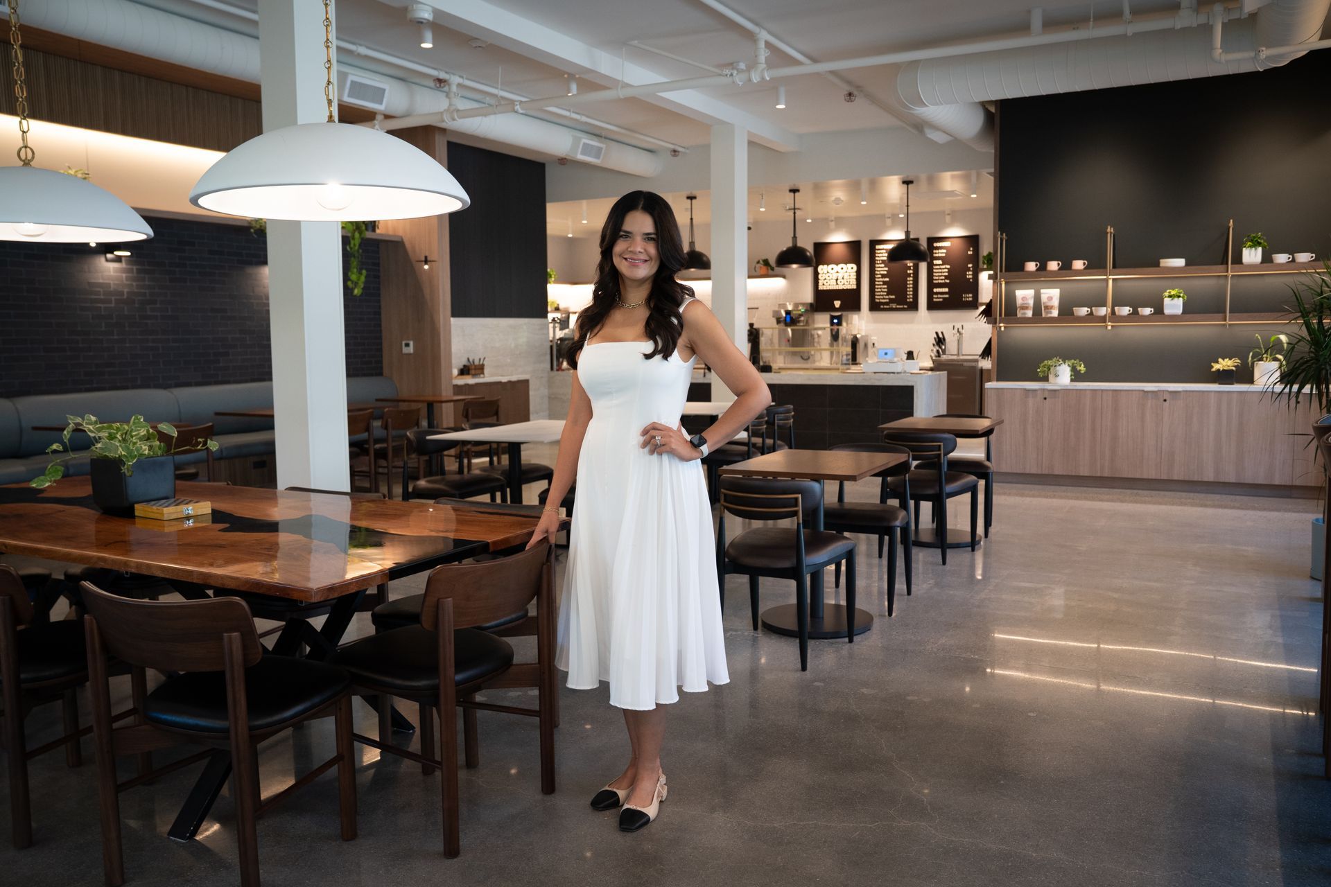 Woman in a white dress standing in a modern restaurant dining area