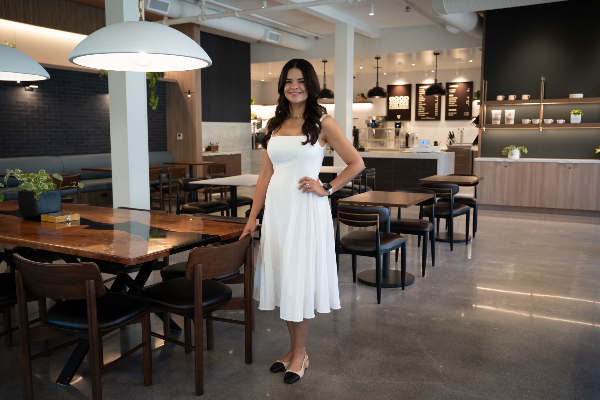 Woman in a white dress standing in a modern restaurant dining area