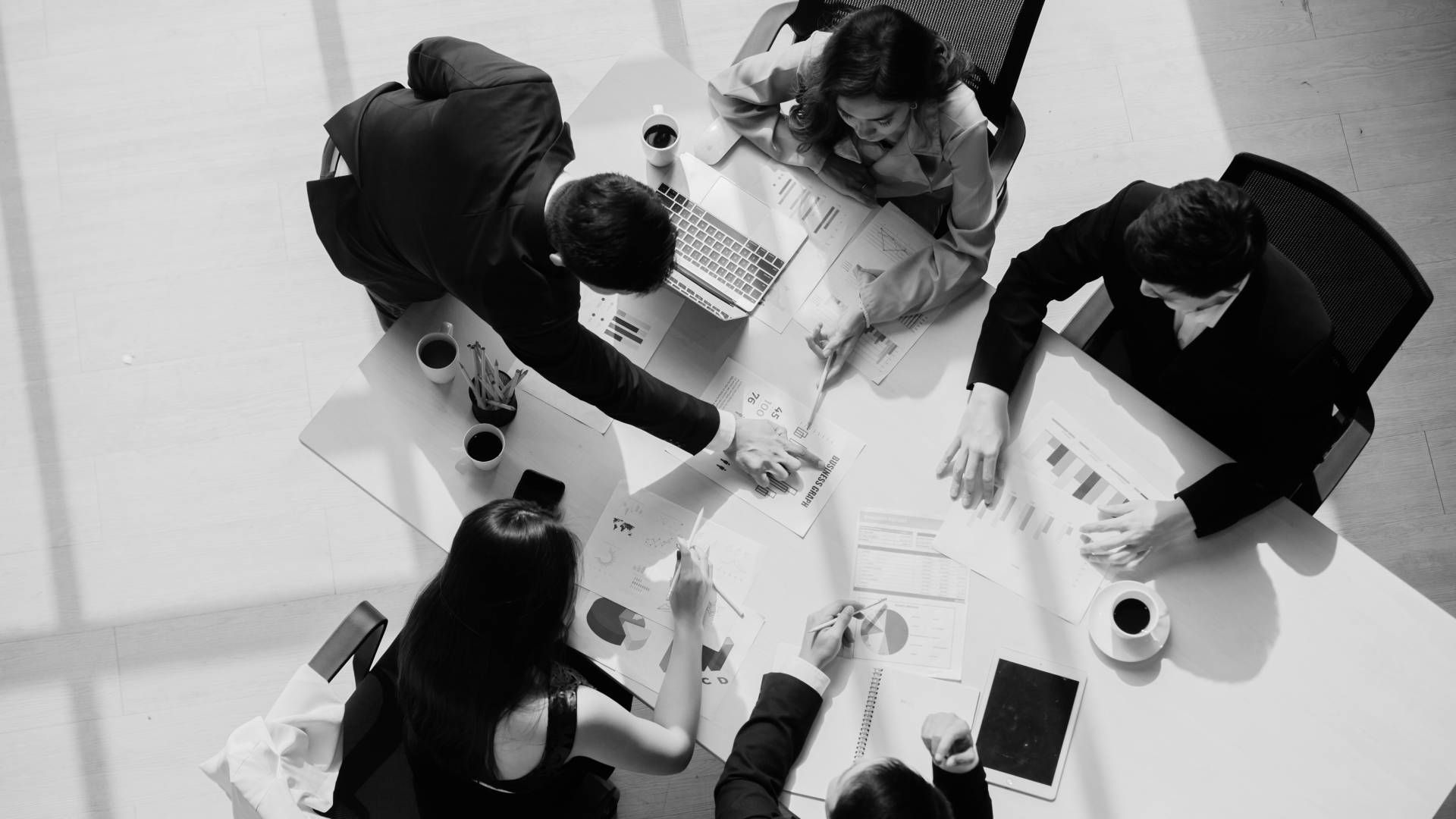 A group of people are sitting around a table shaking hands.