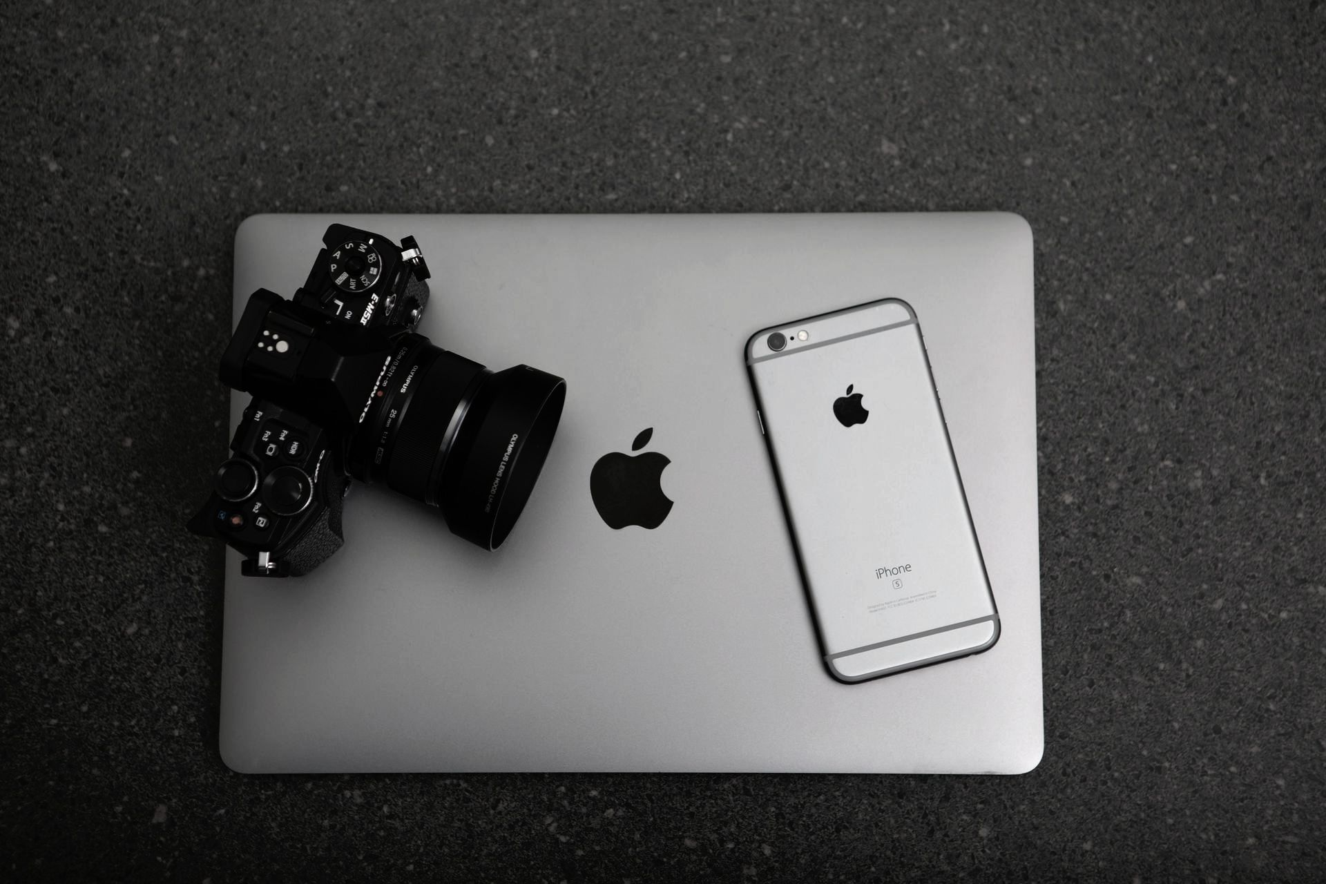 An apple laptop with a camera and a cell phone on it