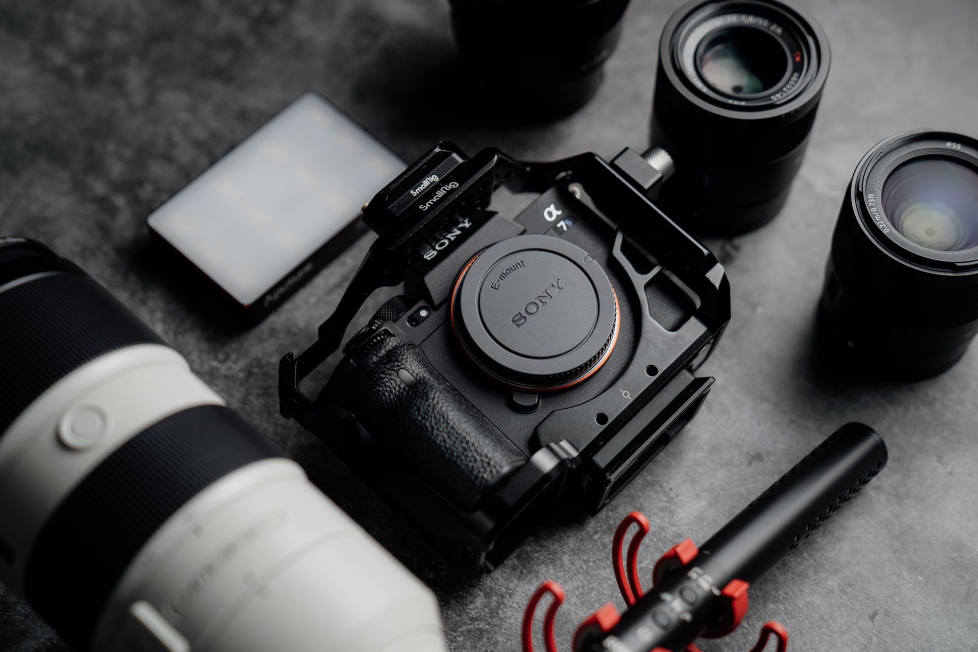 A camera , lenses , and a microphone are on a table.