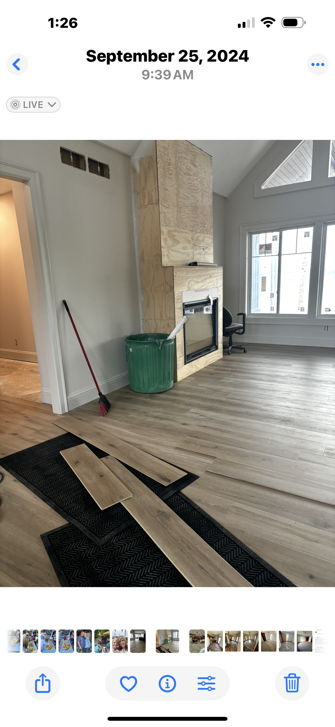 Open-concept living space with wood floors, kitchen, dining area, and living room with large windows overlooking a yard.