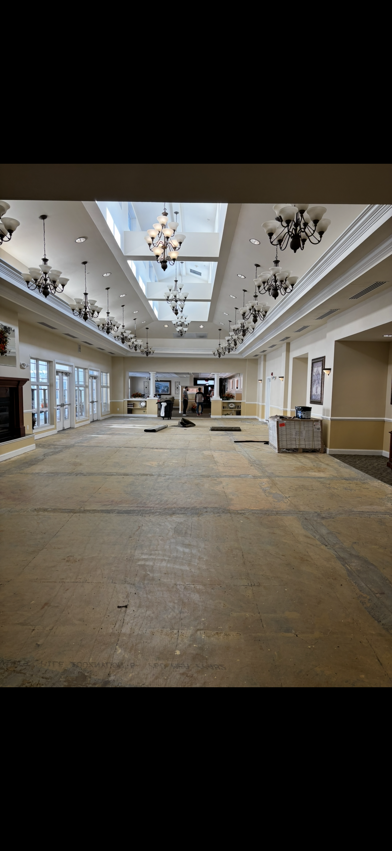 Large empty room, likely a ballroom, with chandeliers and skylights.