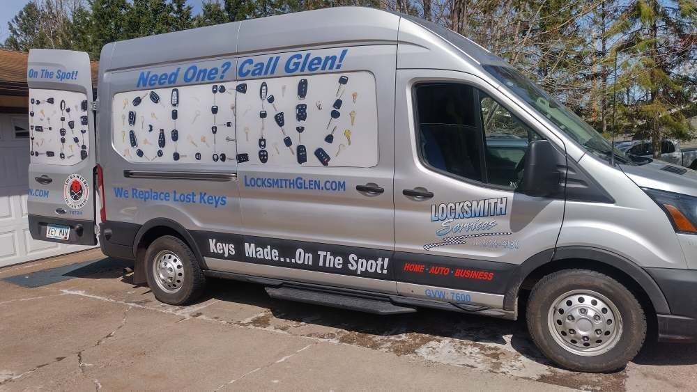 Silver service van with large advertising decals parked on a street in bright sun