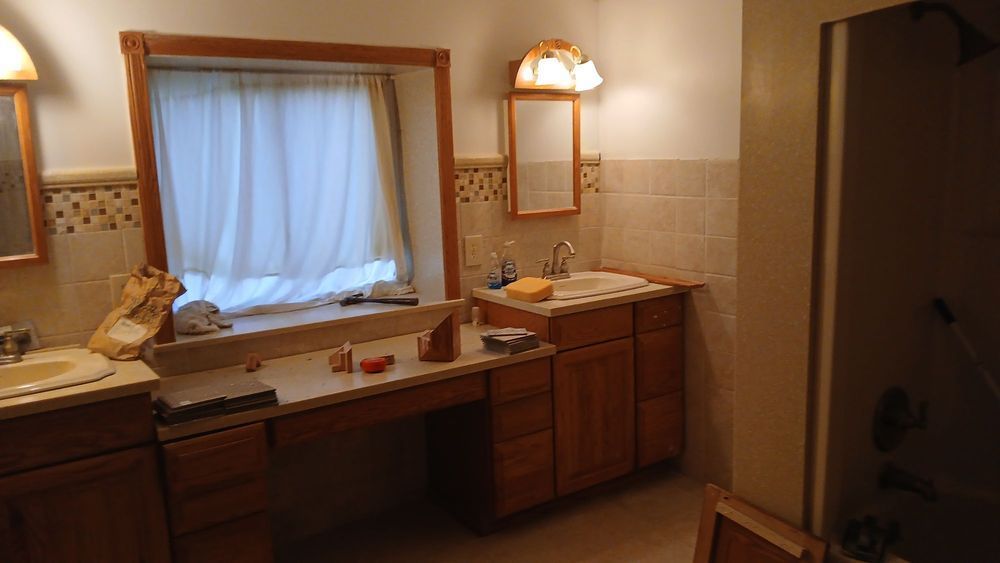 Bathroom vanity with double sinks, mirrors, and warm lighting