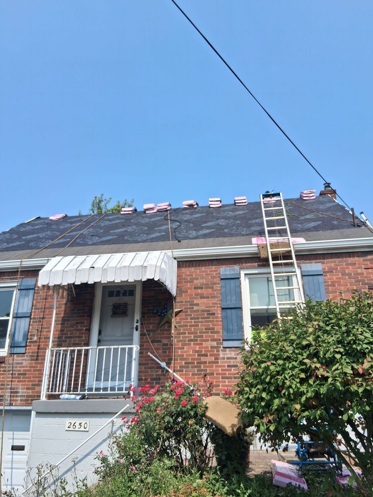 Brick row house with a ladder on the roof and a front porch under a blue sky