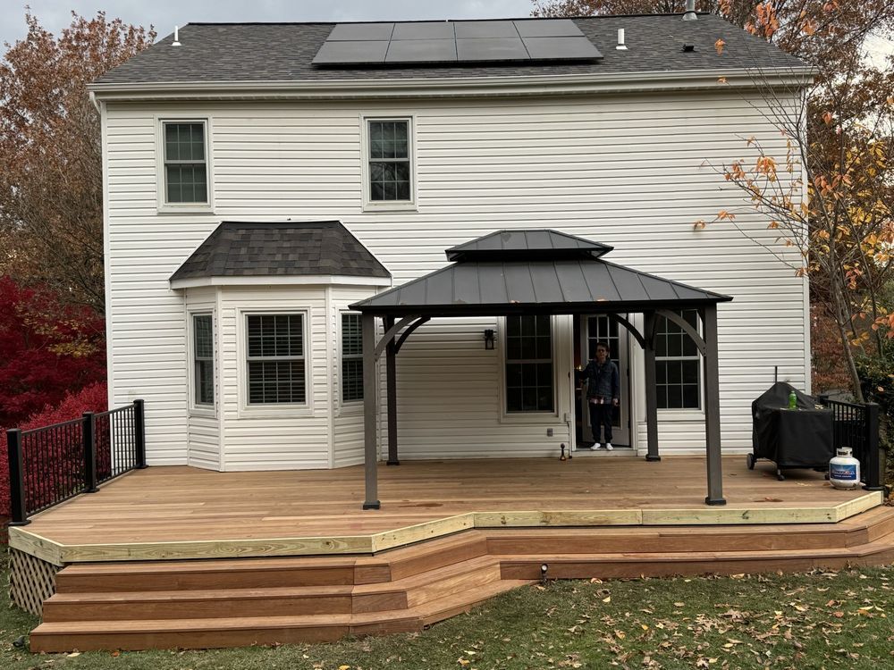 Two-story house with rear deck, covered patio, and wooden steps leading to the yard.