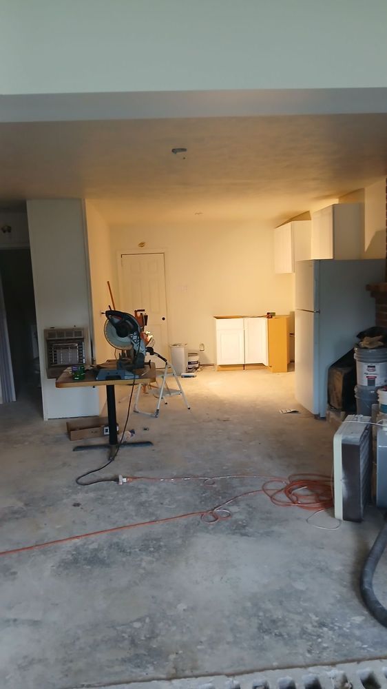 Renovation in progress in an unfinished room with tools, cords, and exposed concrete floor