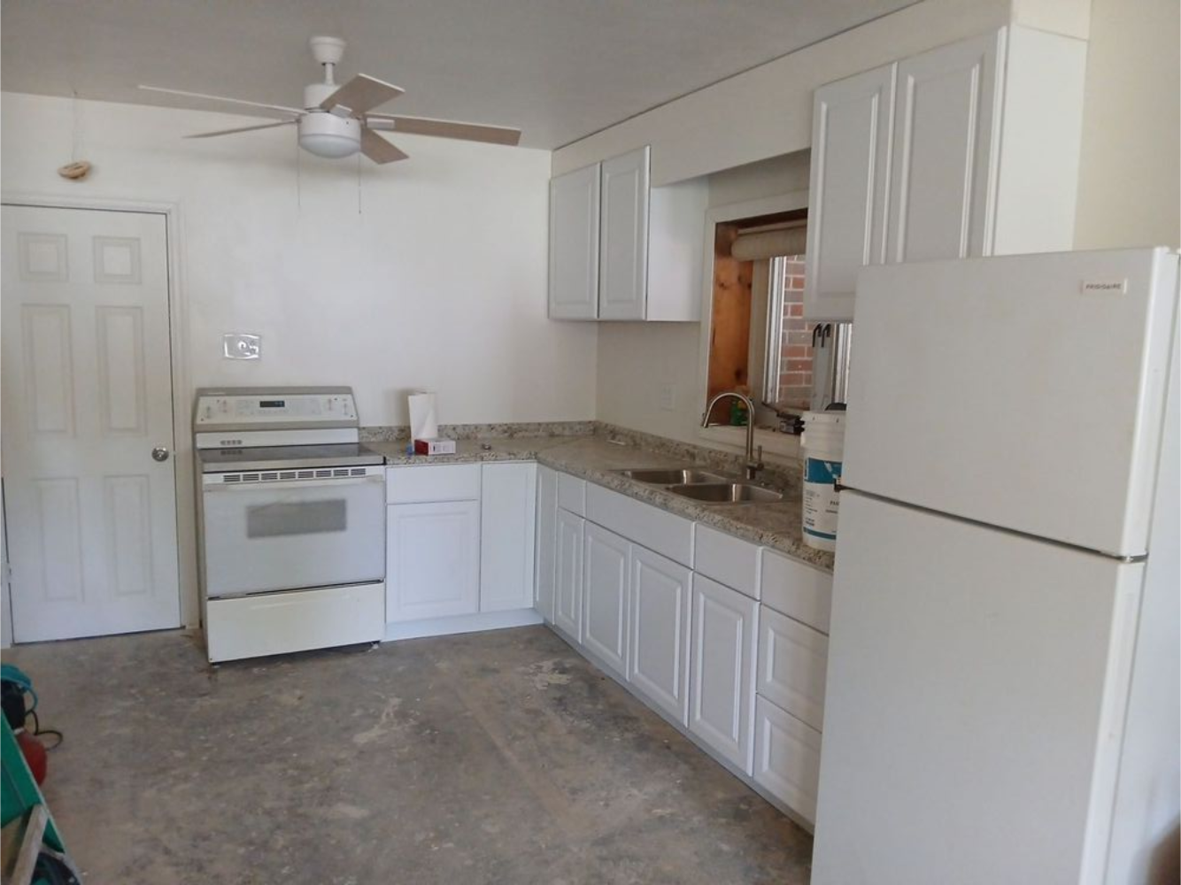 Bright kitchen with white cabinets, stainless steel appliances, and a gray tile floor.