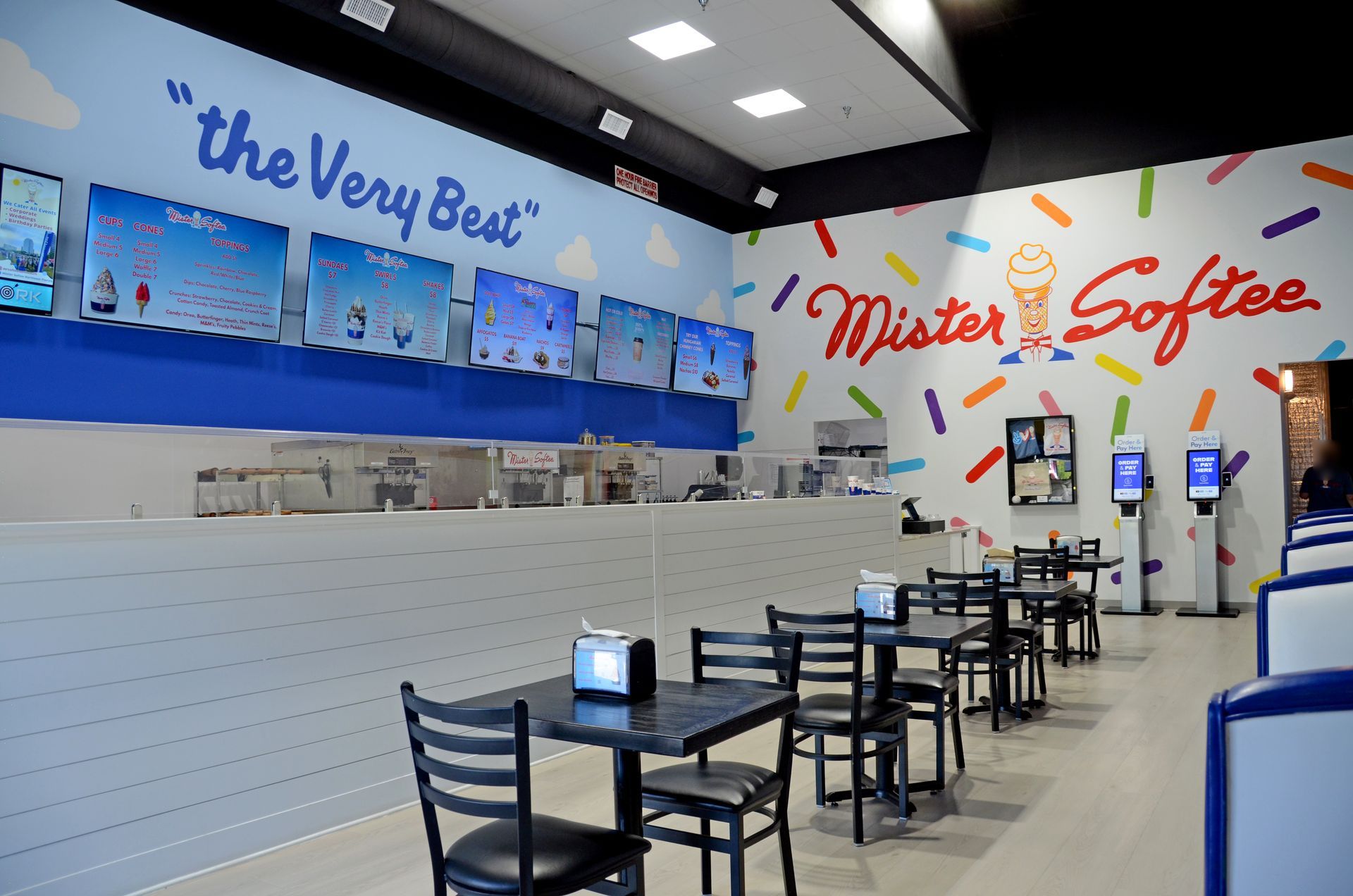 Empty coffee shop interior with blue walls, counter seating, and “Mickie’s Coffee” signage