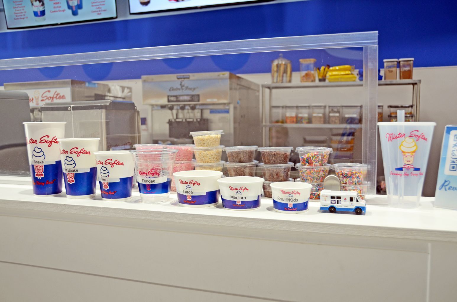 Dairy dessert counter with cups and tubs of frozen yogurt in a bright shop display case