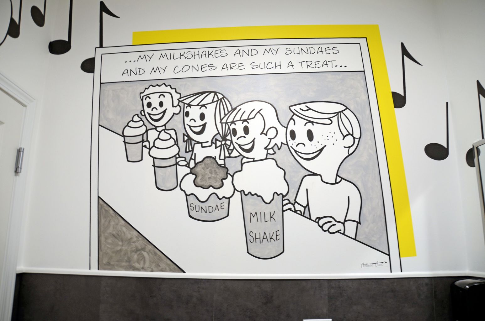Cartoon of four people at a table with drinks and cupcakes, framed by a yellow border on a wall