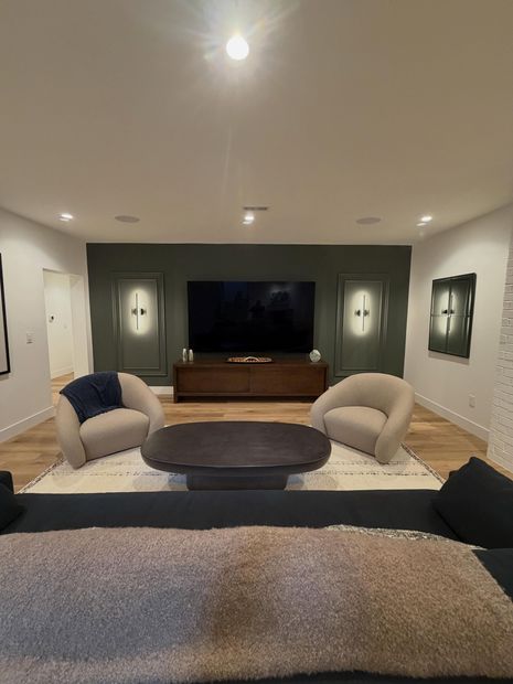 Modern living room with sectional sofa, round coffee table, TV, and framed wall art
