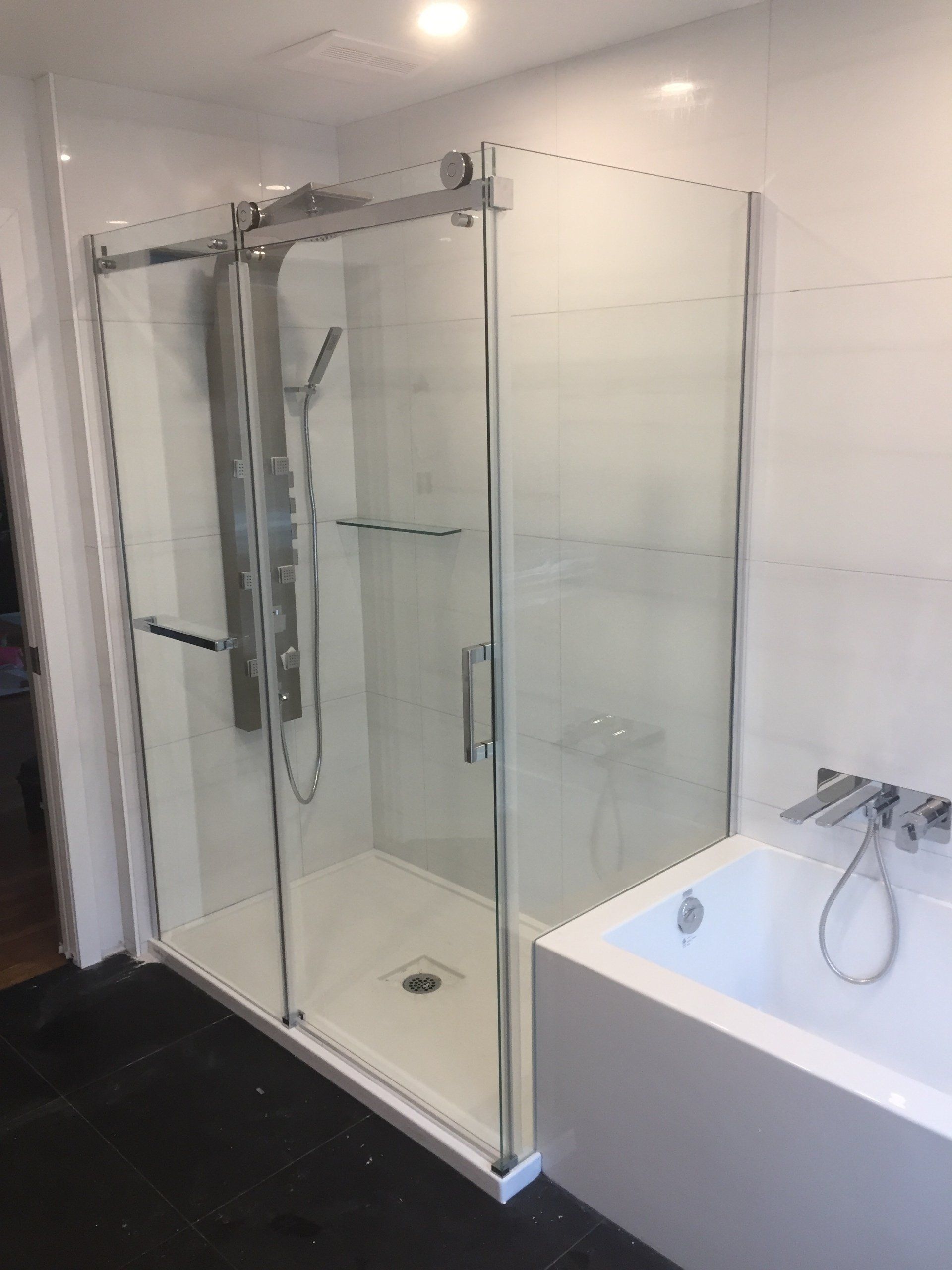 Salle de bains moderne avec une cabine de douche en verre à côté d'une baignoire blanche.